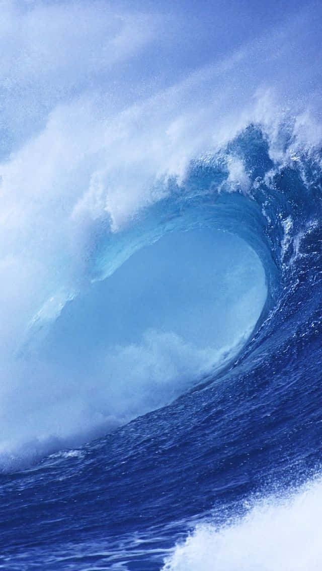  壁紙 — 巨大的藍綠色海浪捲成完美的筒狀，帶著泡沫般的白色水花，映襯著清澈的藍天。