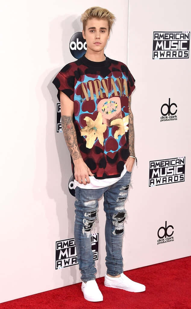 Justin Bieber 2015 桌布 壁紙 — Justin Bieber 在美國音樂獎的紅地毯上，穿著 Nirvana 圖案 T 恤、破洞牛仔褲和白色運動鞋。