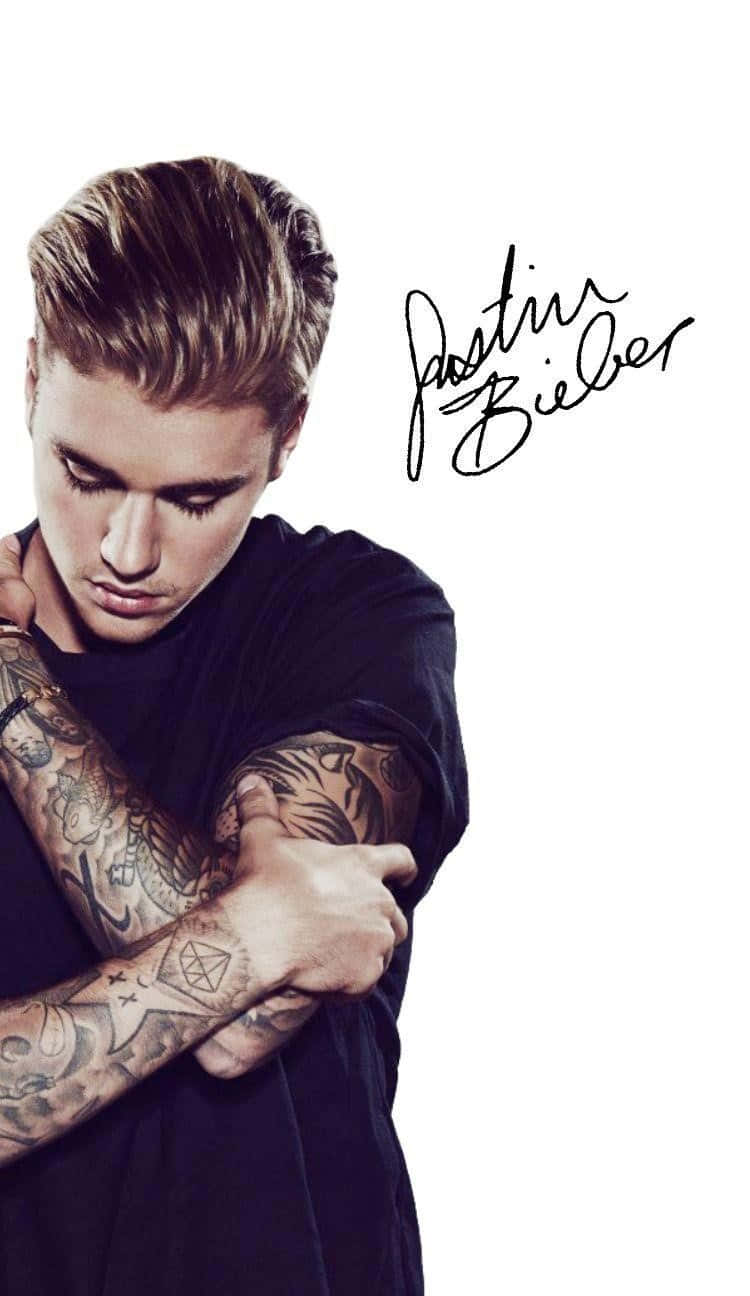 小賈斯汀 桌布 壁紙 — Justin Bieber 將有刺青的手臂交叉在胸前，背景為純白色，並附有他的簽名。