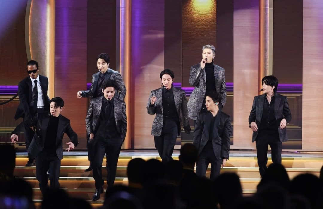 K-pop組合在燈光舞台上跳舞，前景有觀眾。 — Bts 壁紙