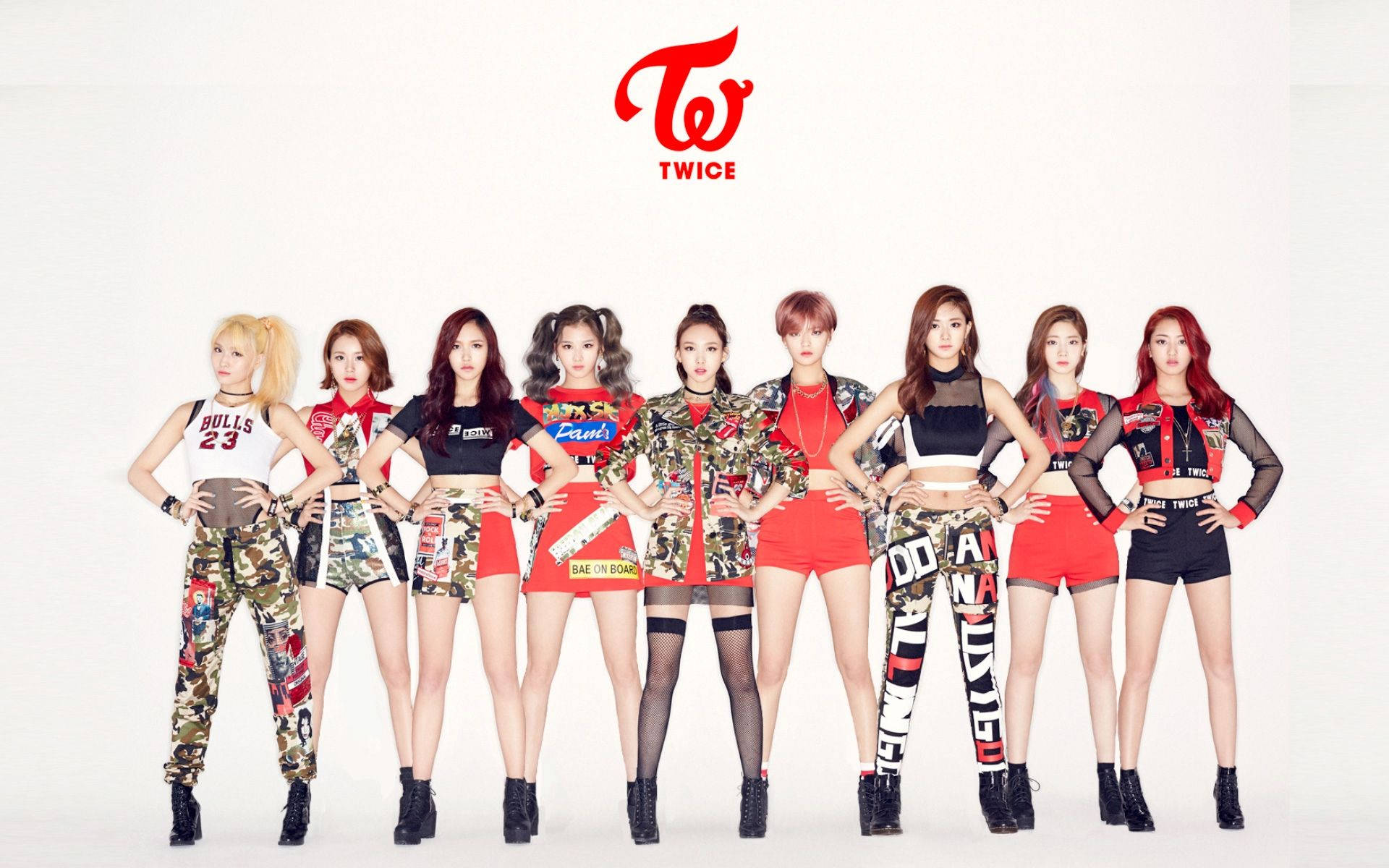 音樂 桌布 壁紙 — K-pop 組合 TWICE 在純白工作室背景下，以鮮紅色迷彩和圖案服裝自信地擺出姿勢。