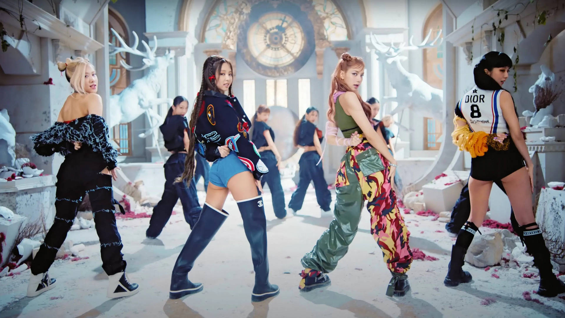 K Pop 桌布 壁紙 — K-pop 舞者穿著大膽街頭服飾，在超現實、灑滿雪的大教堂中擺出動感姿勢，周圍有發光的鹿雕塑和散落的玫瑰花瓣。