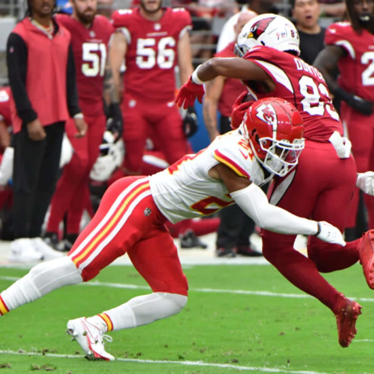  壁紙 — 一名堪薩斯城酋長隊球員在充滿活力的綠色球場上進行NFL比賽時，向前猛衝進行兇猛的擒抱。