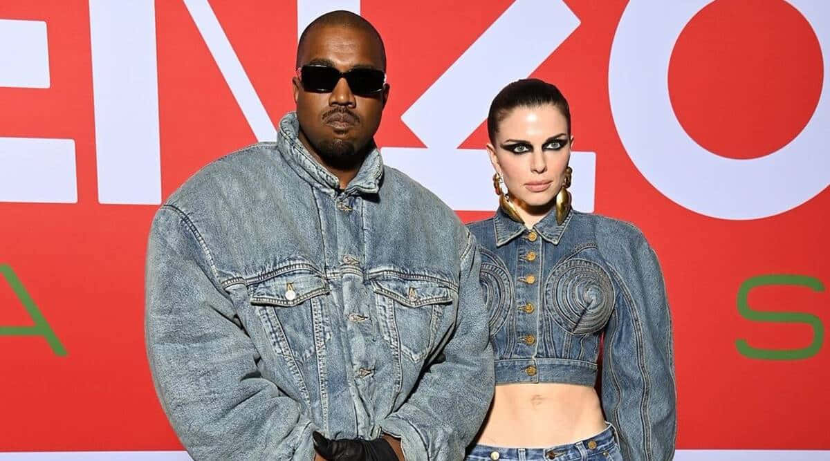 Julia Fox 桌布 壁紙 — Kanye West 和一位穿著牛仔服裝的女性在一個大膽的紅白品牌背景前自信地擺姿勢。