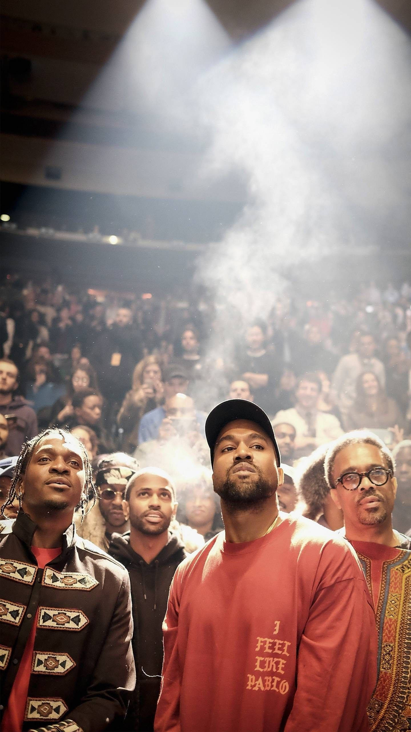 說唱歌手 桌布 壁紙 — Kanye West 和朋友們站在舞台中央，明亮的聚光燈下，煙霧在他們周圍旋轉，人群在下方觀看。