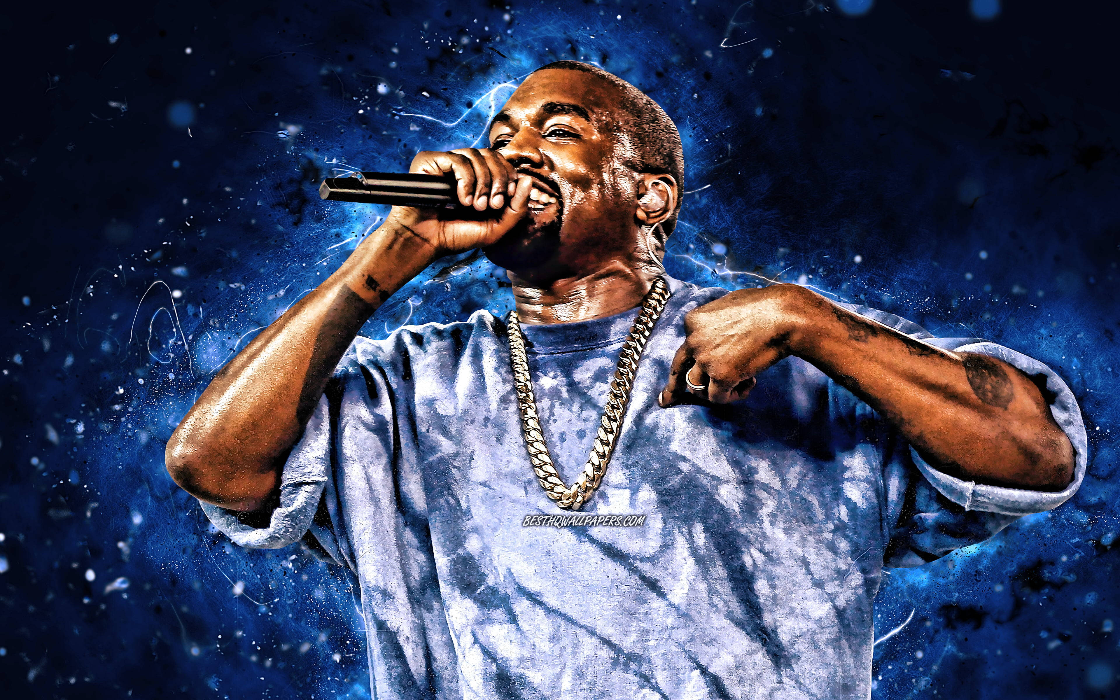 Kanye West Ye 桌布 壁紙 — Kanye West 對著麥克風熱情地說唱，背景是帶有發光粒子的宇宙藍色。