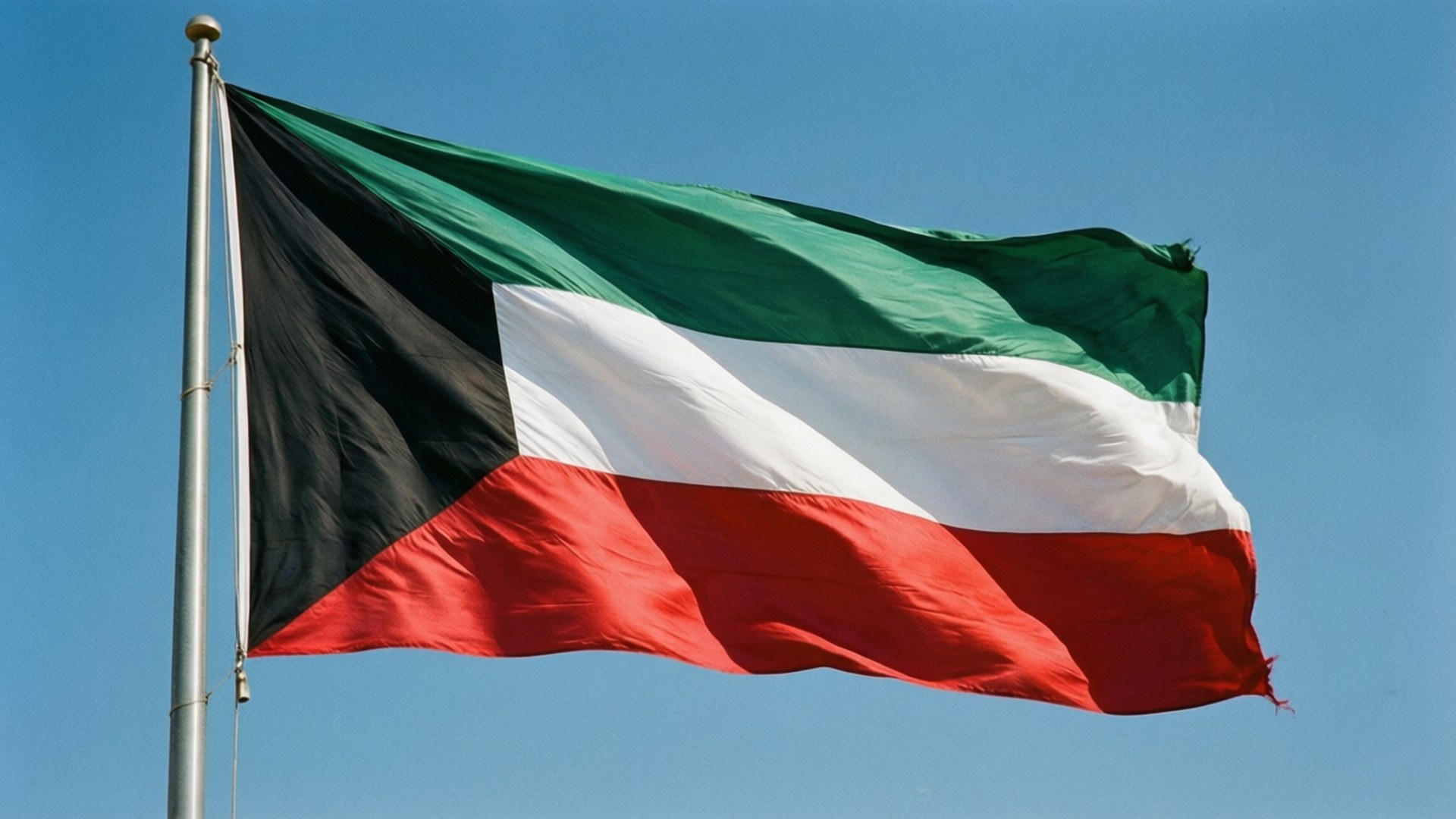 Kuwait Flag Waving 壁紙 — 科威特國旗上的黑色、綠色、白色和紅色條紋在清澈的藍天下動態飄揚。