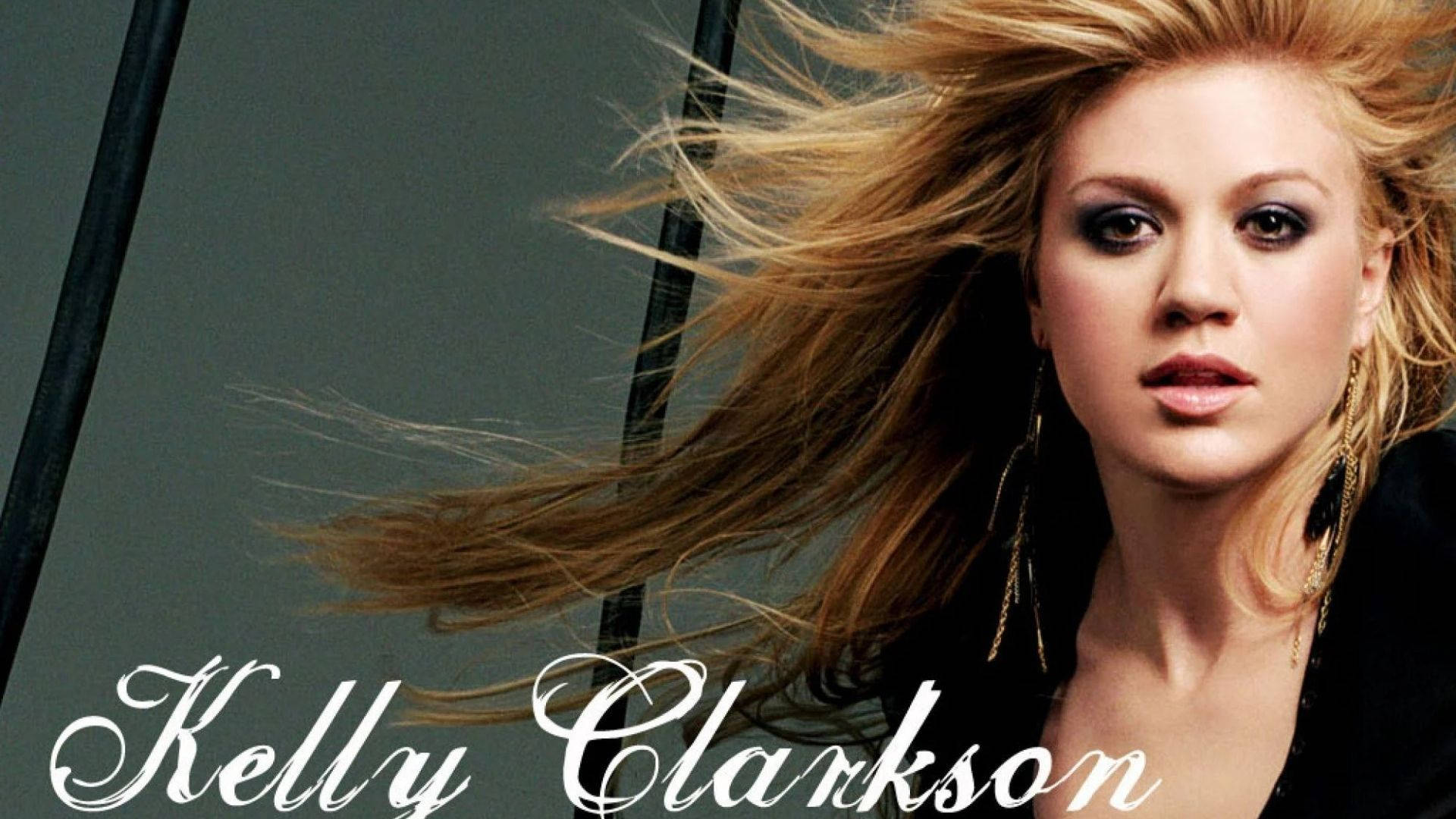 凱莉·克萊森 桌布 壁紙 — Kelly Clarkson 一頭被風吹拂的金髮和煙燻眼妝，在深灰色背景下強烈凝視。