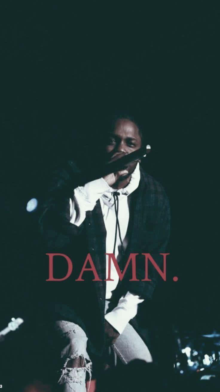Aesthetic Rapper 桌布 壁紙 — Kendrick Lamar 在昏暗燈光下於舞台上手持麥克風，並有紅色文字 DAMN。