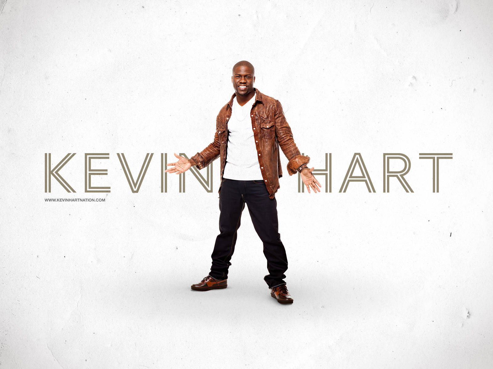 Kevin Hart 穿著棕色皮外套微笑，他的名字顯示在身後。 — Michael B Jordan 壁紙