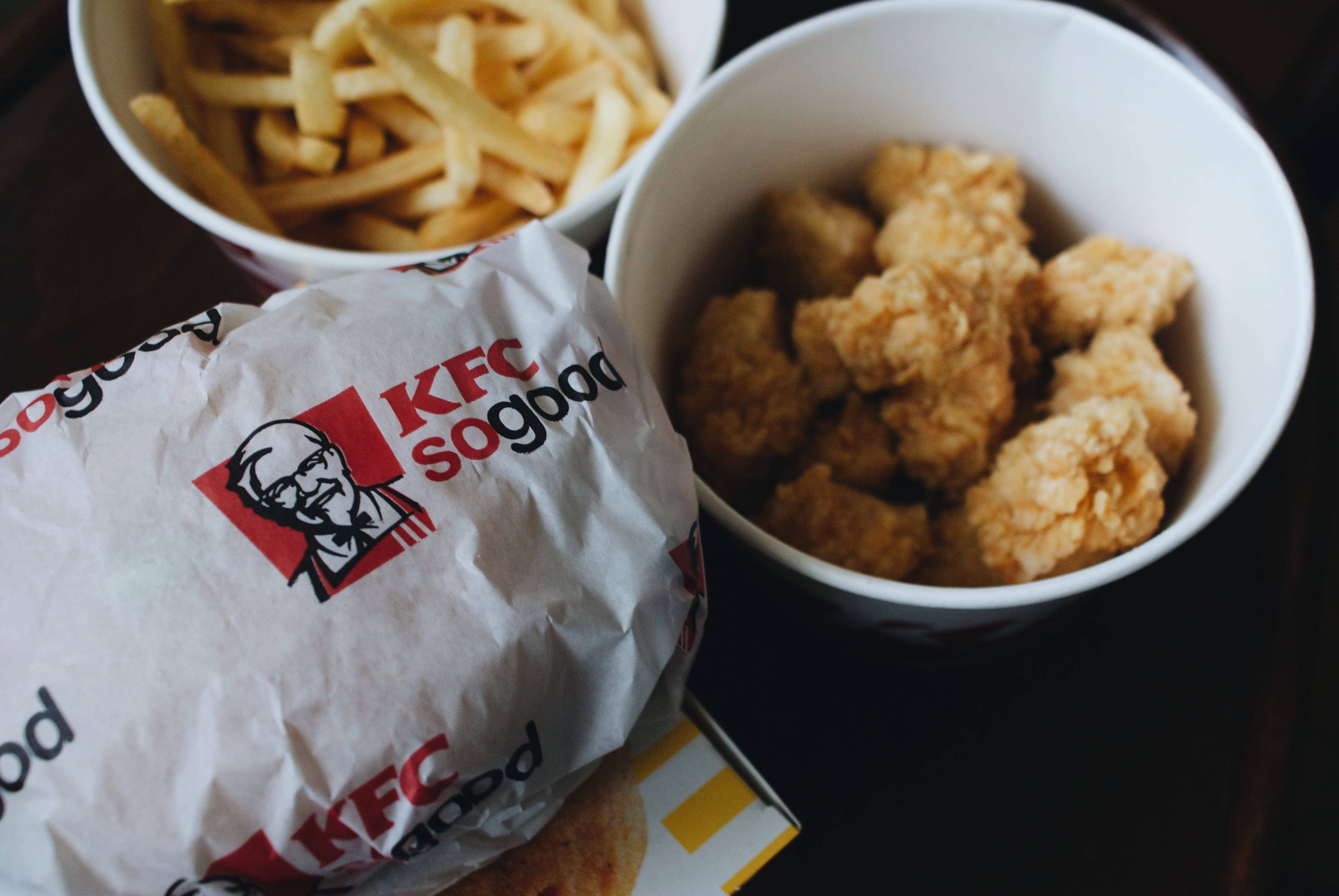 Kfc 桌布 壁紙 — KFC 餐點的近距離特寫，包括酥脆的炸雞塊和金黃色薯條，放在品牌紙張和碗中。