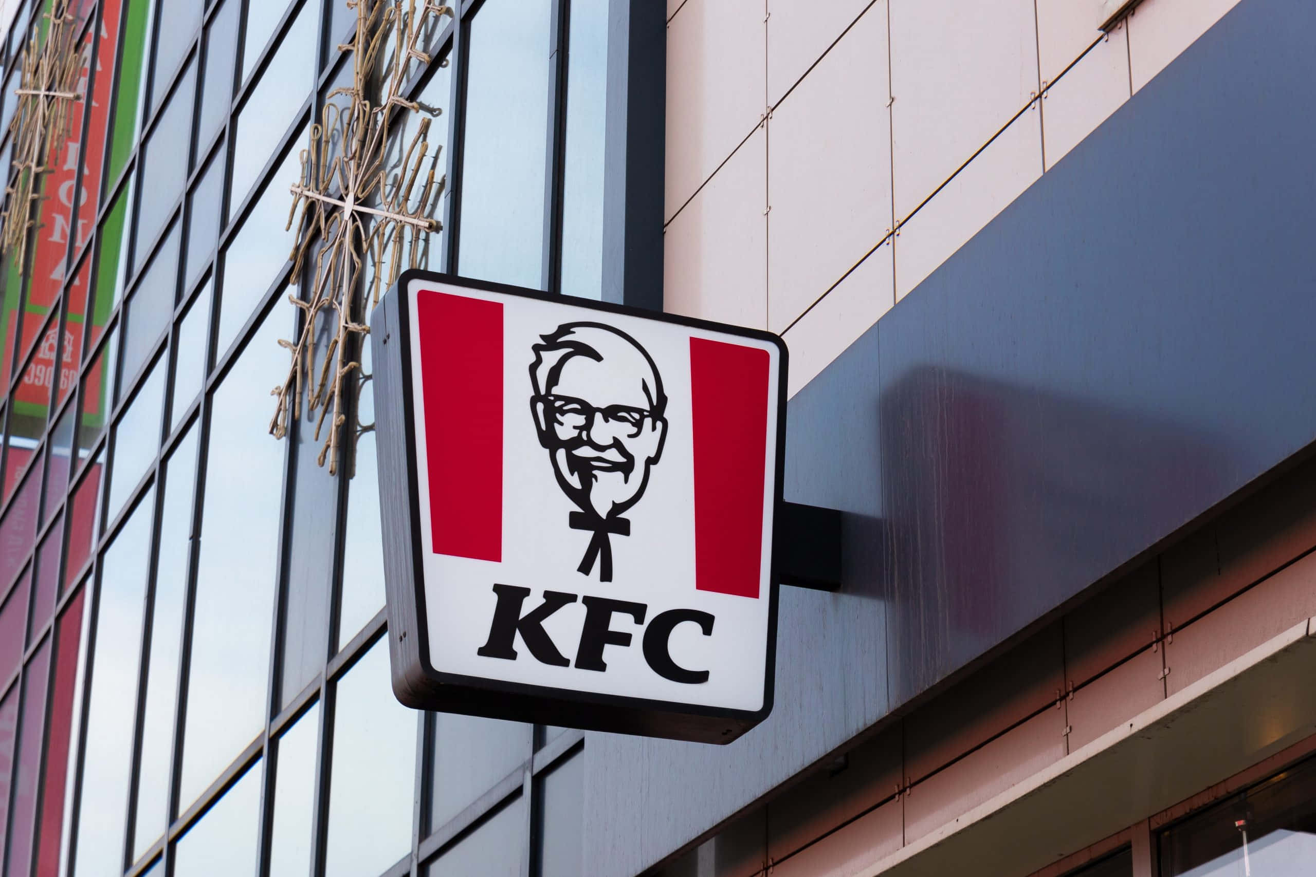 肯德基 桌布 壁紙 — KFC餐廳招牌的特寫，上面有山德士上校的肖像，安裝在現代建築的外牆上。
