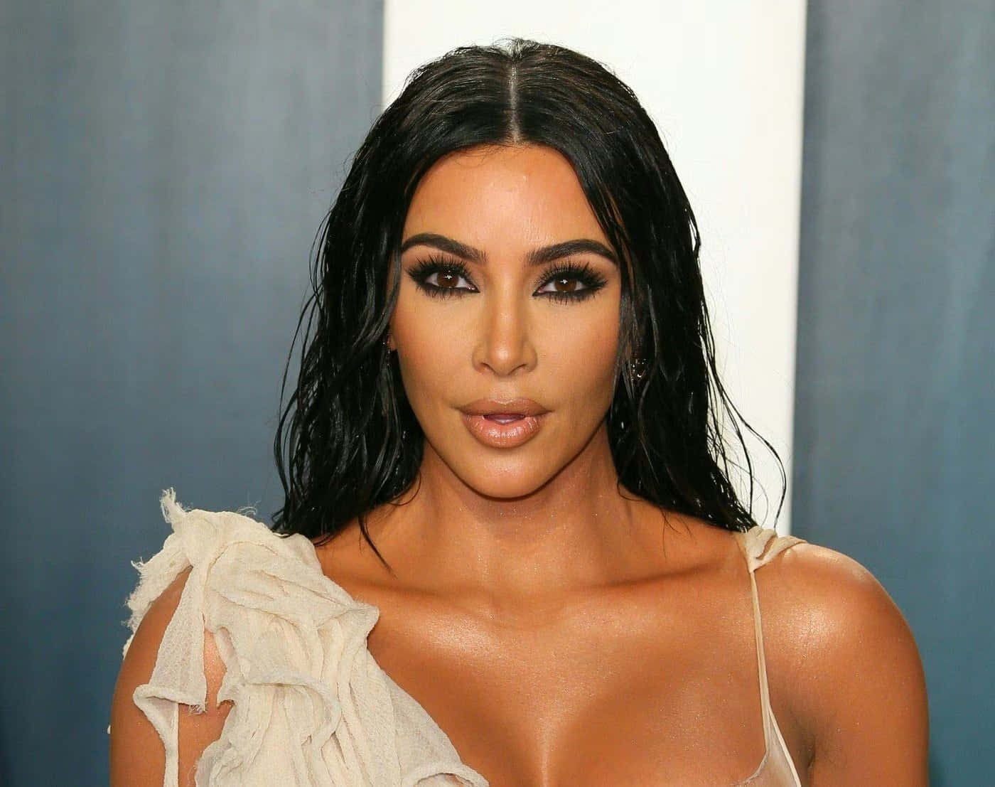 Kim Kardashian 桌布 壁紙 — Kim Kardashian 以濕黑髮和鮮豔妝容在藍白背景前擺姿勢。
