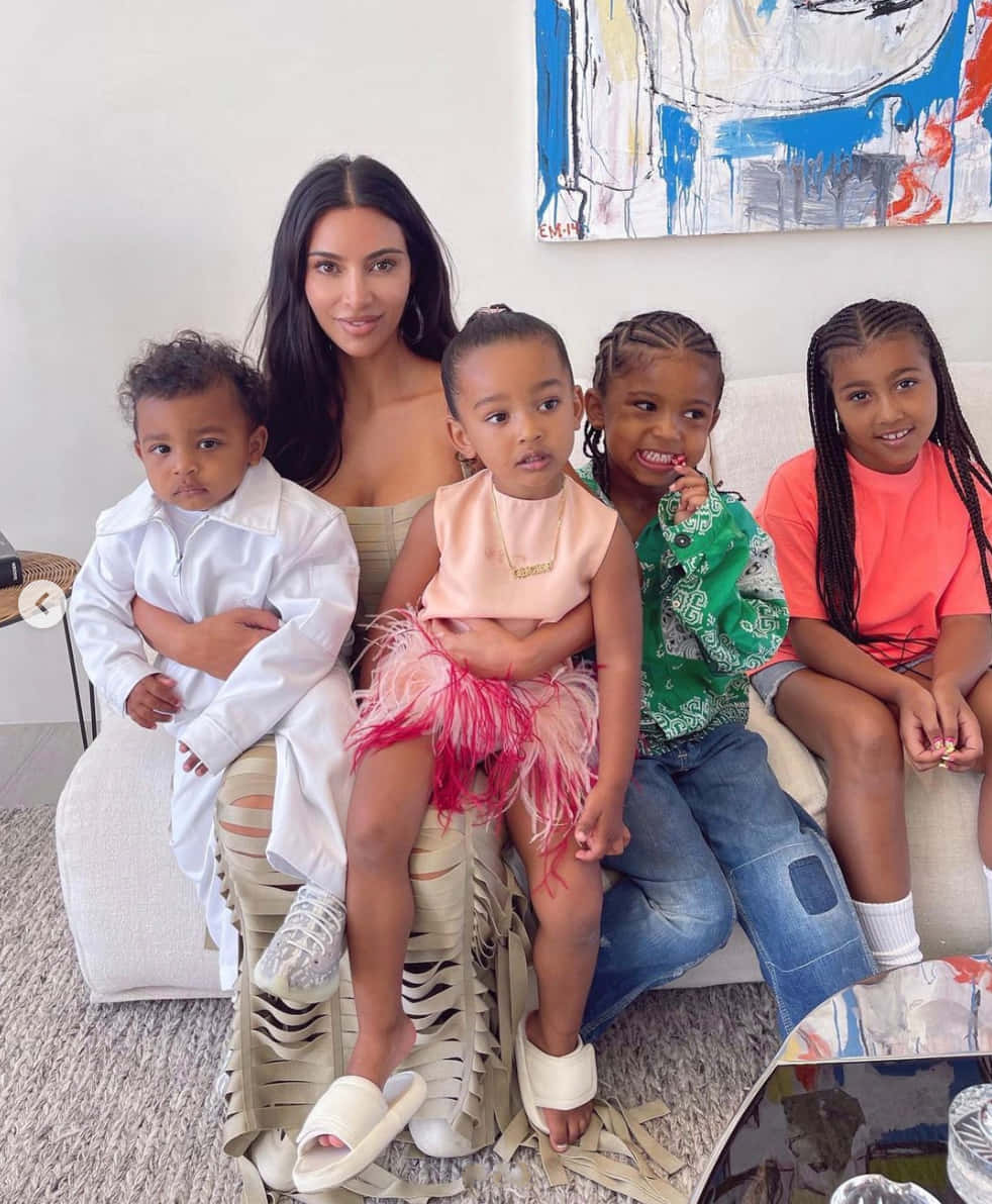 Baby 桌布 壁紙 — Kim Kardashian 和她的四個孩子一起在現代沙發上擺姿勢，身處明亮簡約的客廳，牆上掛著抽象藝術品。