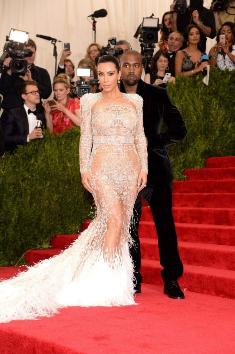 Met Gala 桌布 壁紙 — Kim Kardashian 身穿驚豔的白色羽毛長裙，在閃光燈中與 Kanye West 一同走紅地毯。