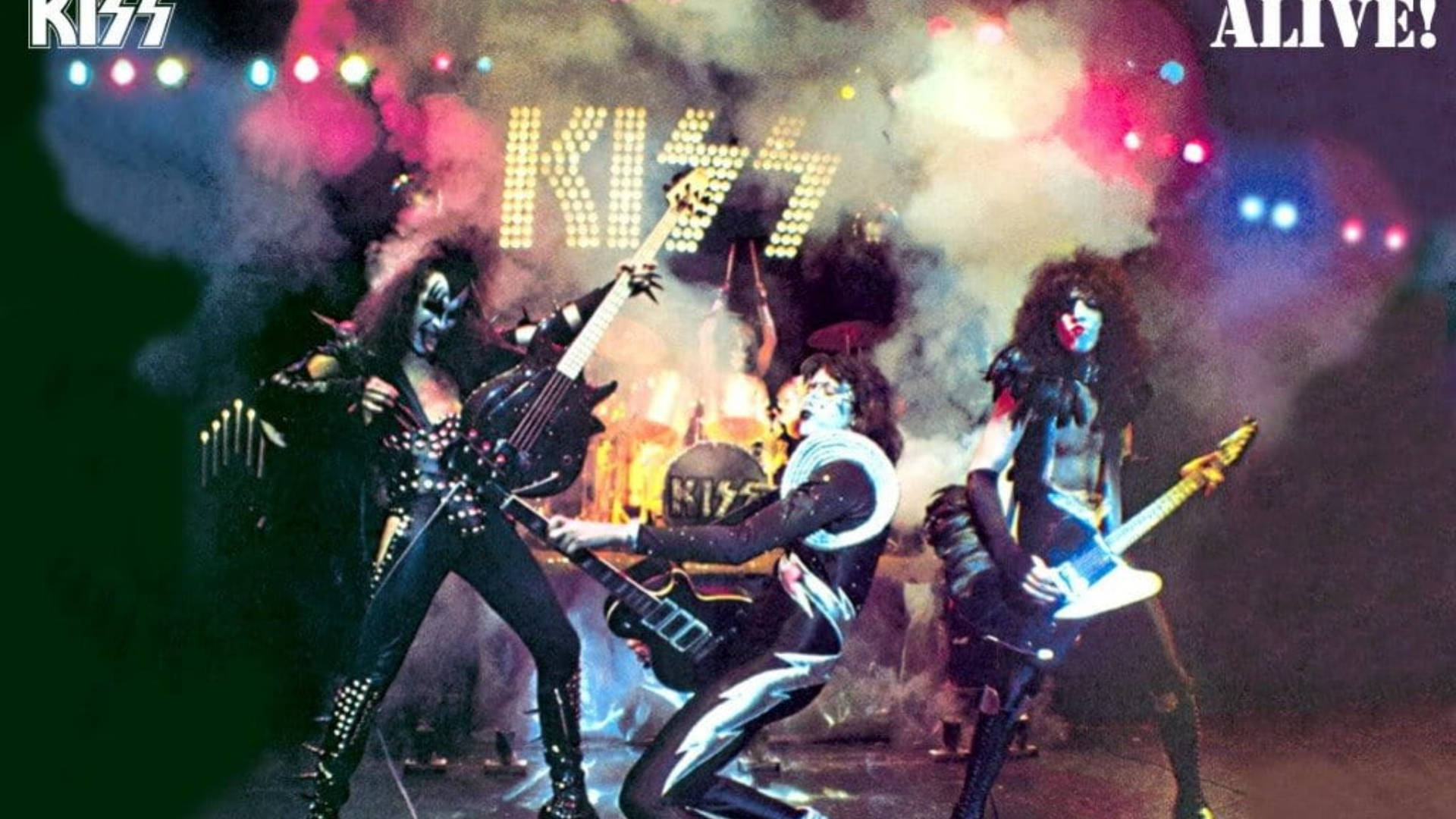 Kiss Band 桌布 壁紙 — KISS 樂團成員以全妝和舞台服裝，在色彩繽紛的燈光和煙霧下充滿活力地表演。