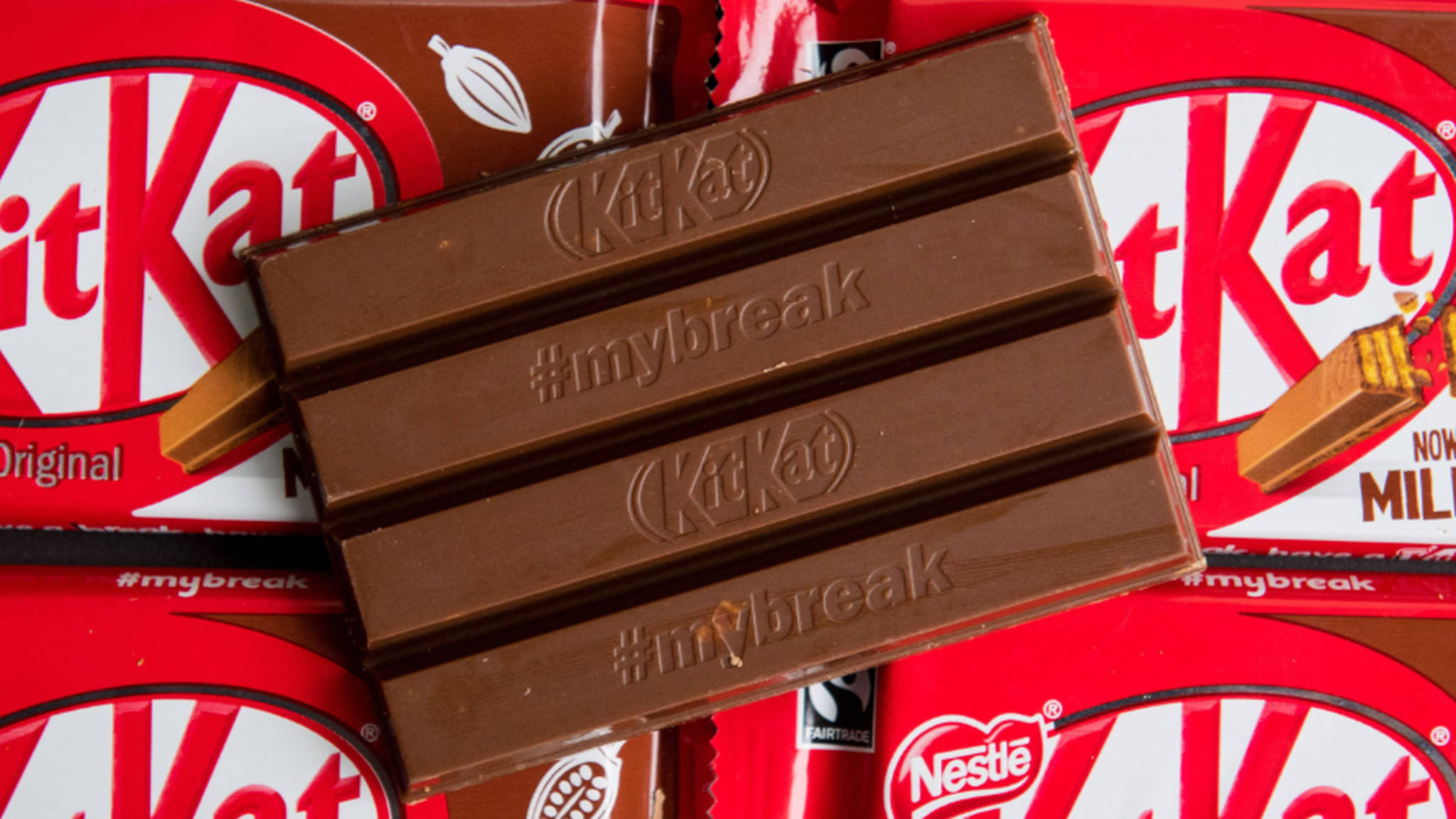 Chocolate 桌布 壁紙 — KitKat 巧克力棒的近距離特寫，其分段上印有 #mybreak，放在紅色 KitKat 包裝紙上。