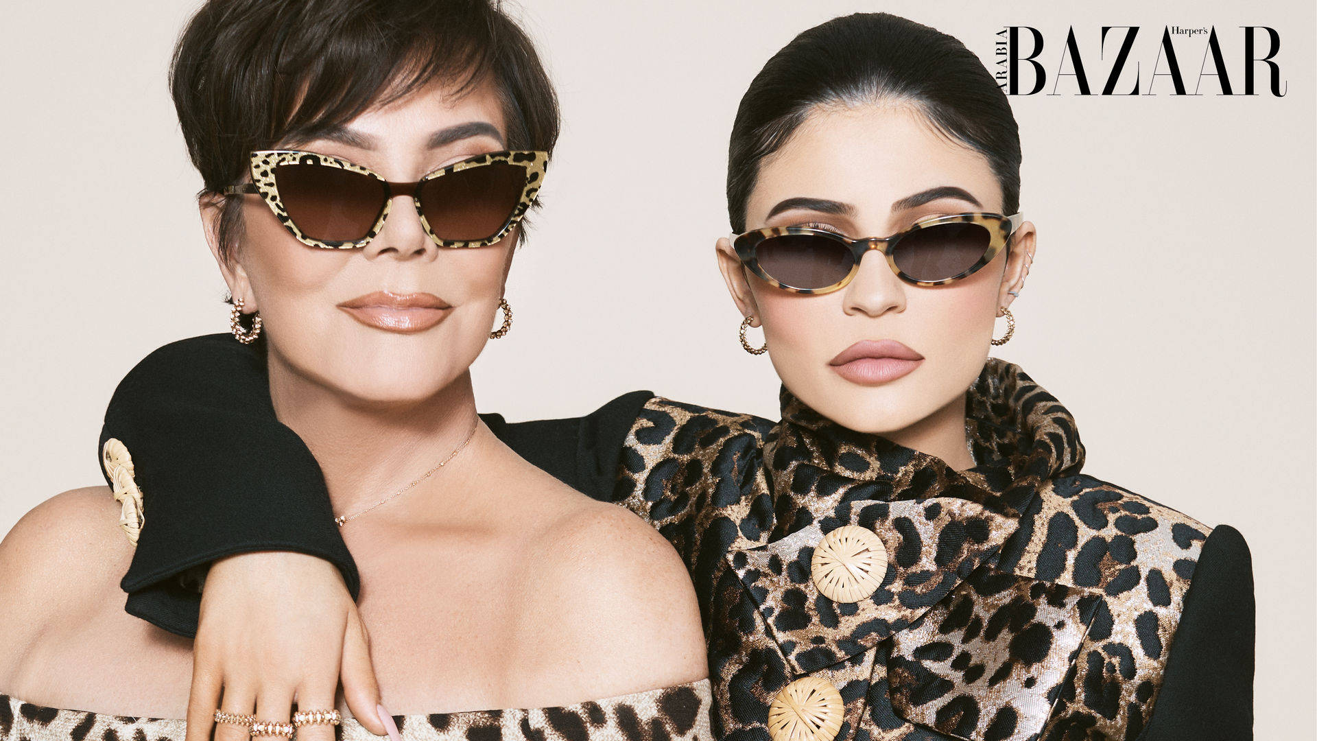 kris 桌布 壁紙 — Kris Jenner 和 Kylie Jenner 穿著相配的豹紋服裝和太陽眼鏡，在中性工作室背景前自信地擺姿勢。