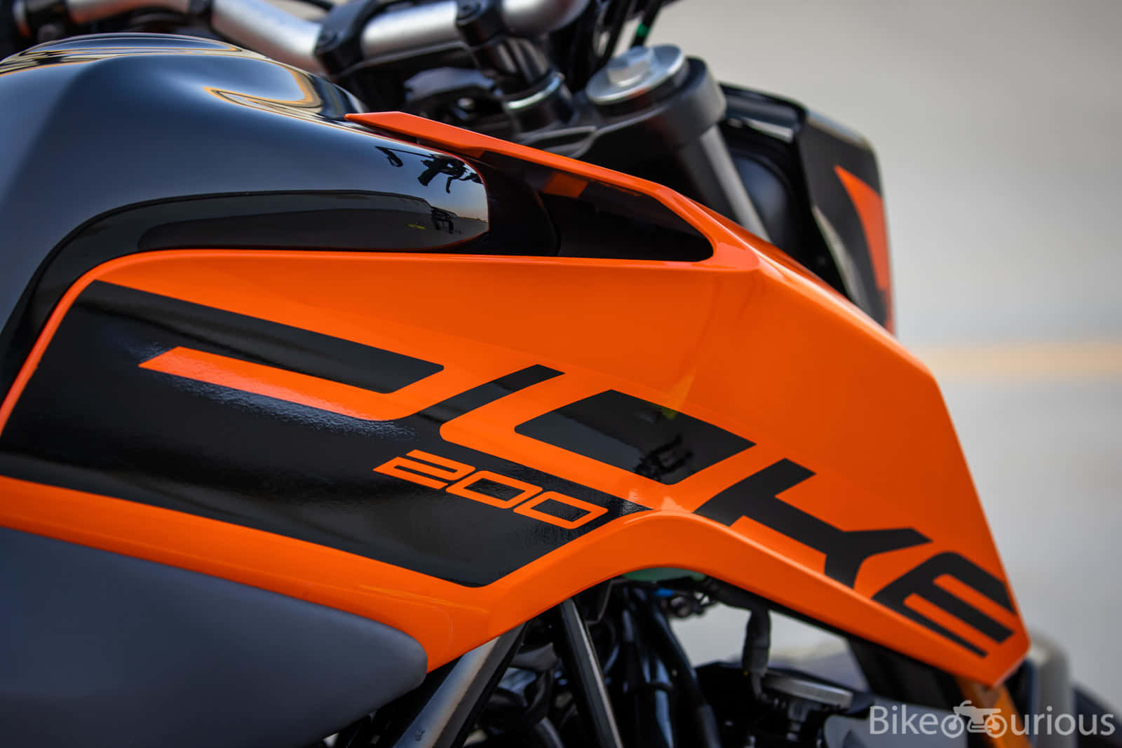  壁紙 — KTM 200機車油箱特寫，鮮豔橙色與黑色，亮面處理，品牌標誌醒目。