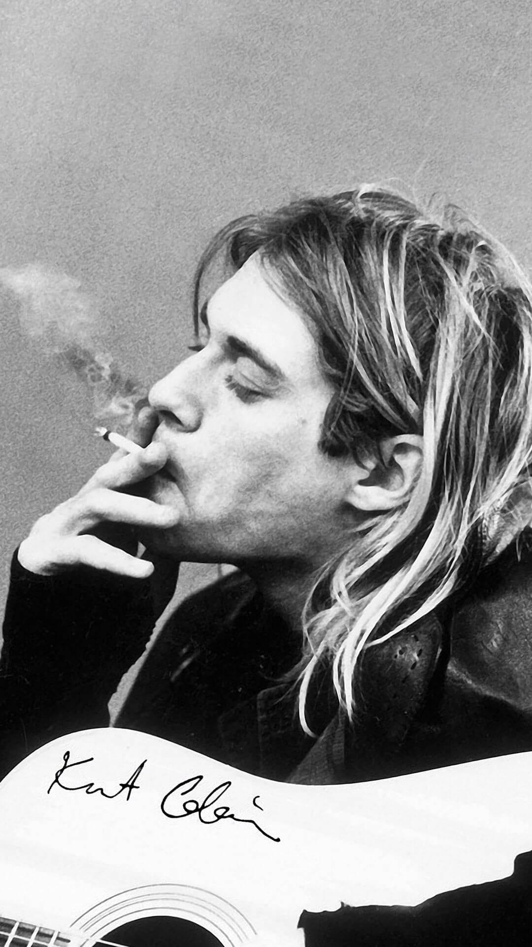 nirvana 4K 桌布 壁紙 — Kurt Cobain 閉著眼睛抽煙，手持一把簽名吉他，呈現出陰鬱的黑白肖像。