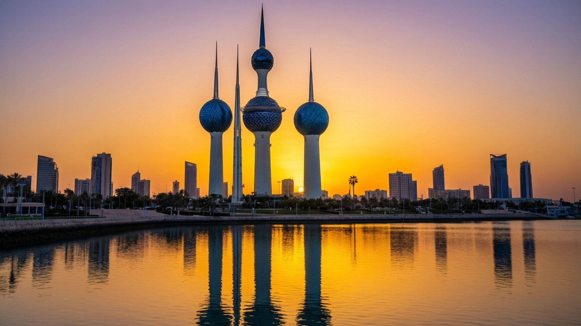 Kuwait Towers Sunset 壁紙 — 科威特塔在金色夕陽天空下高聳，藍色球體倒映在平靜的水面上。