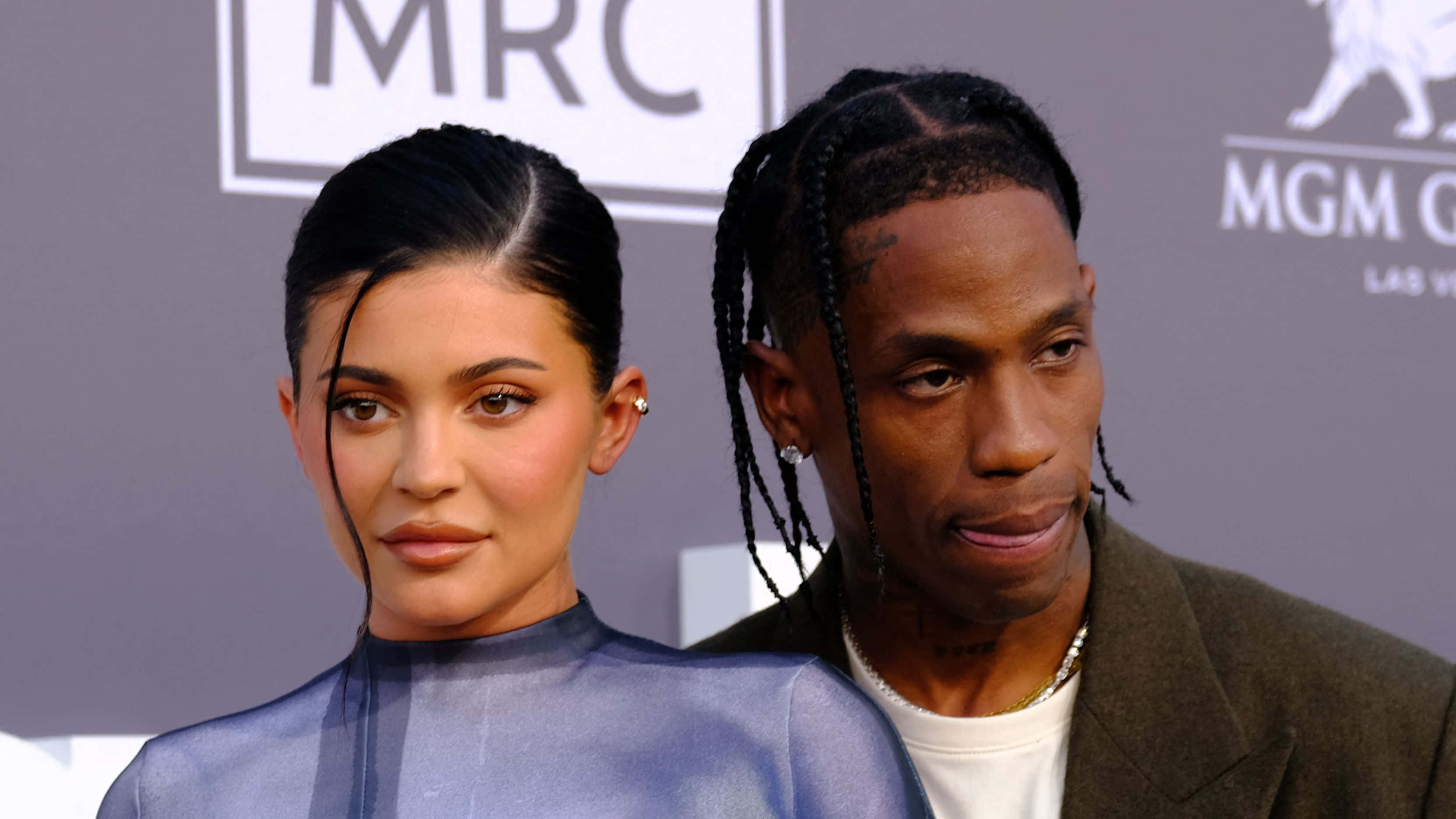 崔維斯·史考特 桌布 壁紙 — Kylie Jenner 和 Travis Scott 在紅地毯活動中一起擺姿勢，背後有品牌背景。