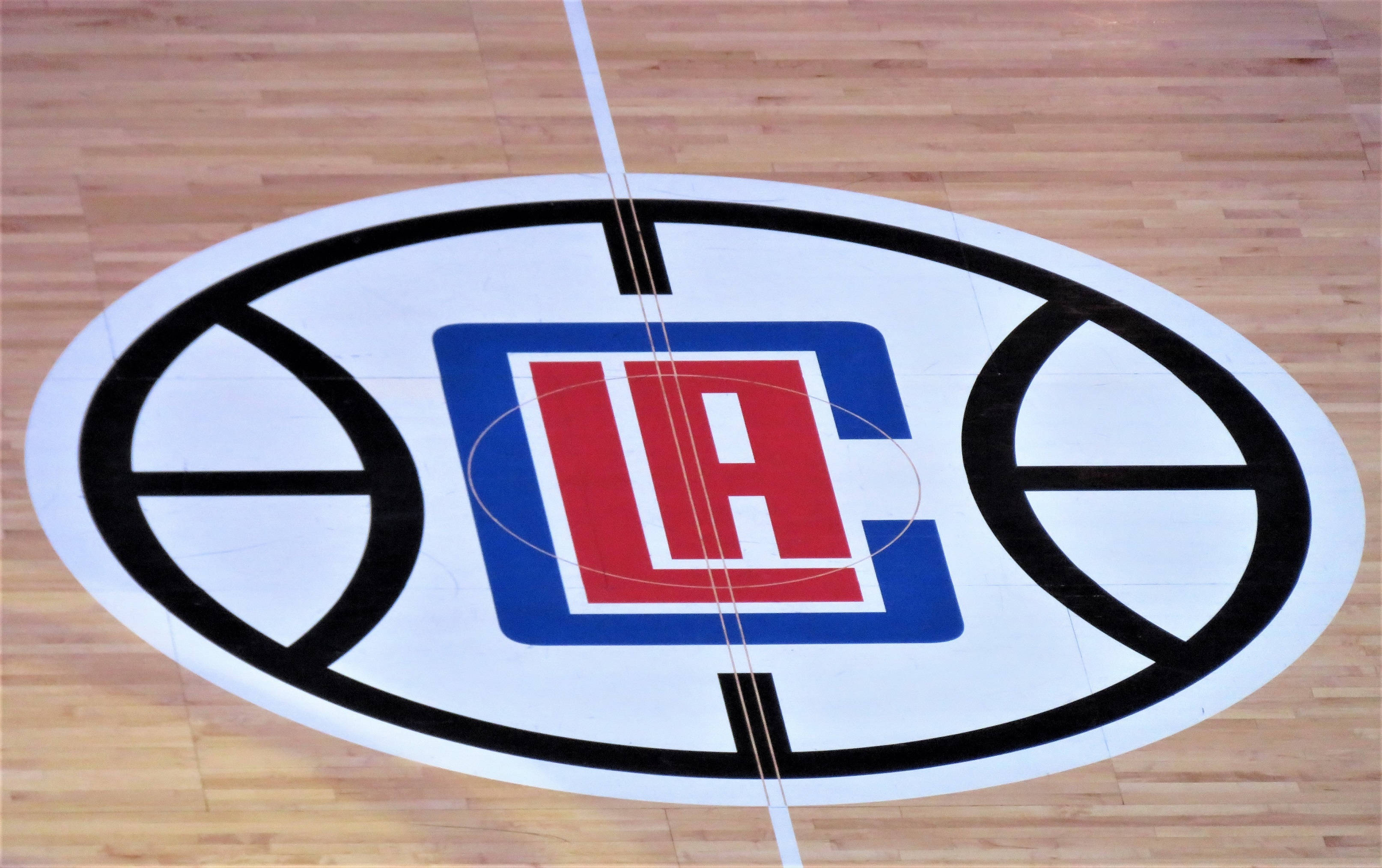 Clippers 桌布 壁紙 — LA Clippers 標誌塗在拋光木質籃球場地板上的俯視圖。