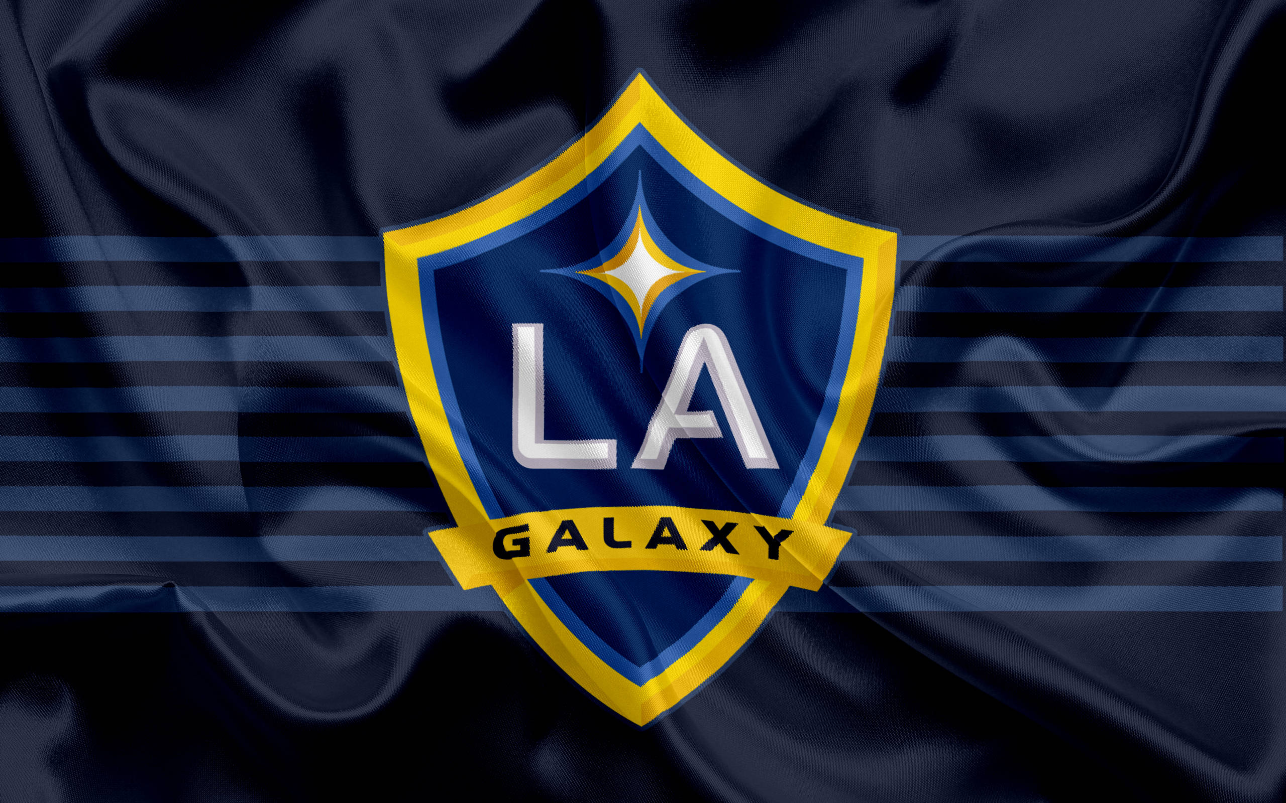 足球 桌布 壁紙 — LA Galaxy 足球隊標誌居中於深藍色緞面旗幟上，帶有水平條紋和星爆徽章。