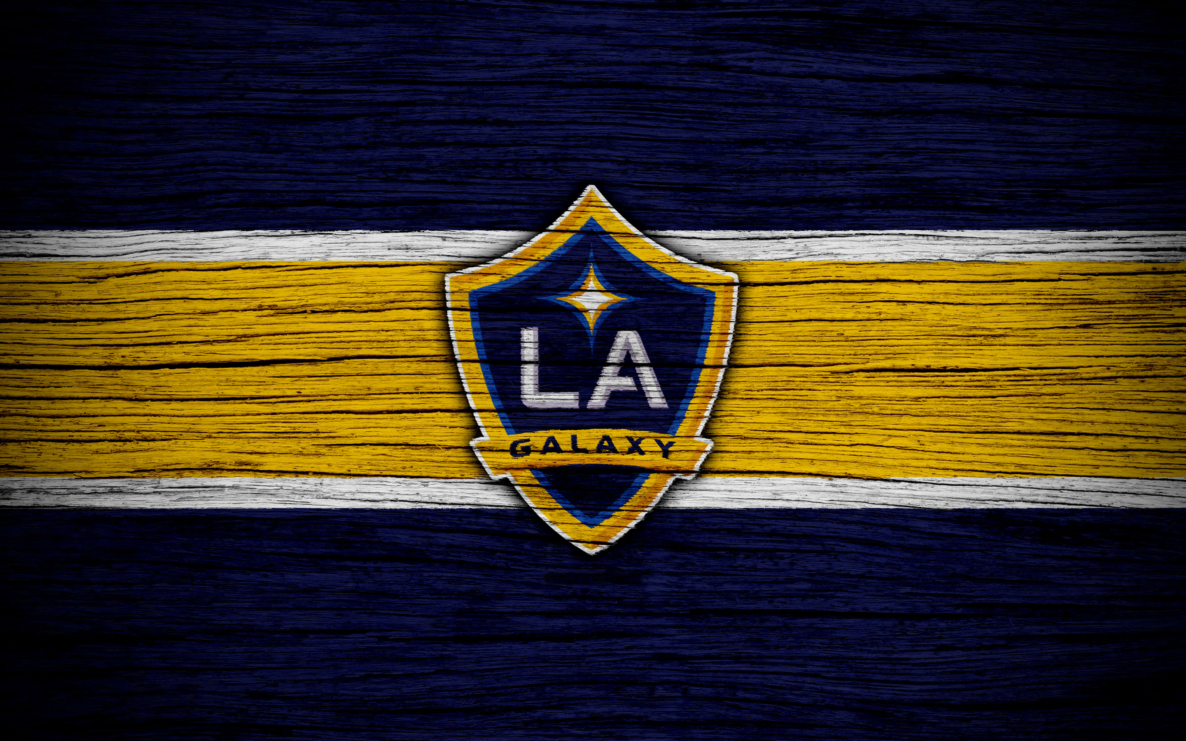4K 桌布 壁紙 — LA Galaxy 足球隊標誌置於風化木質表面中央，搭配大膽的黃藍條紋。