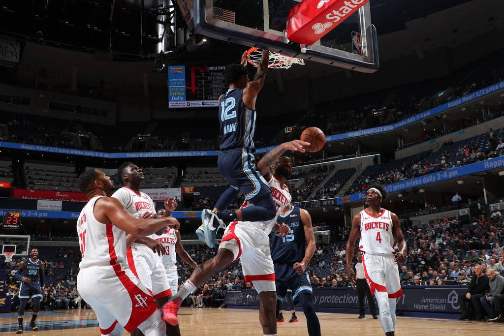 籃球運動員在擠滿觀眾的場館中越過防守球員灌籃。 — NBA 壁紙