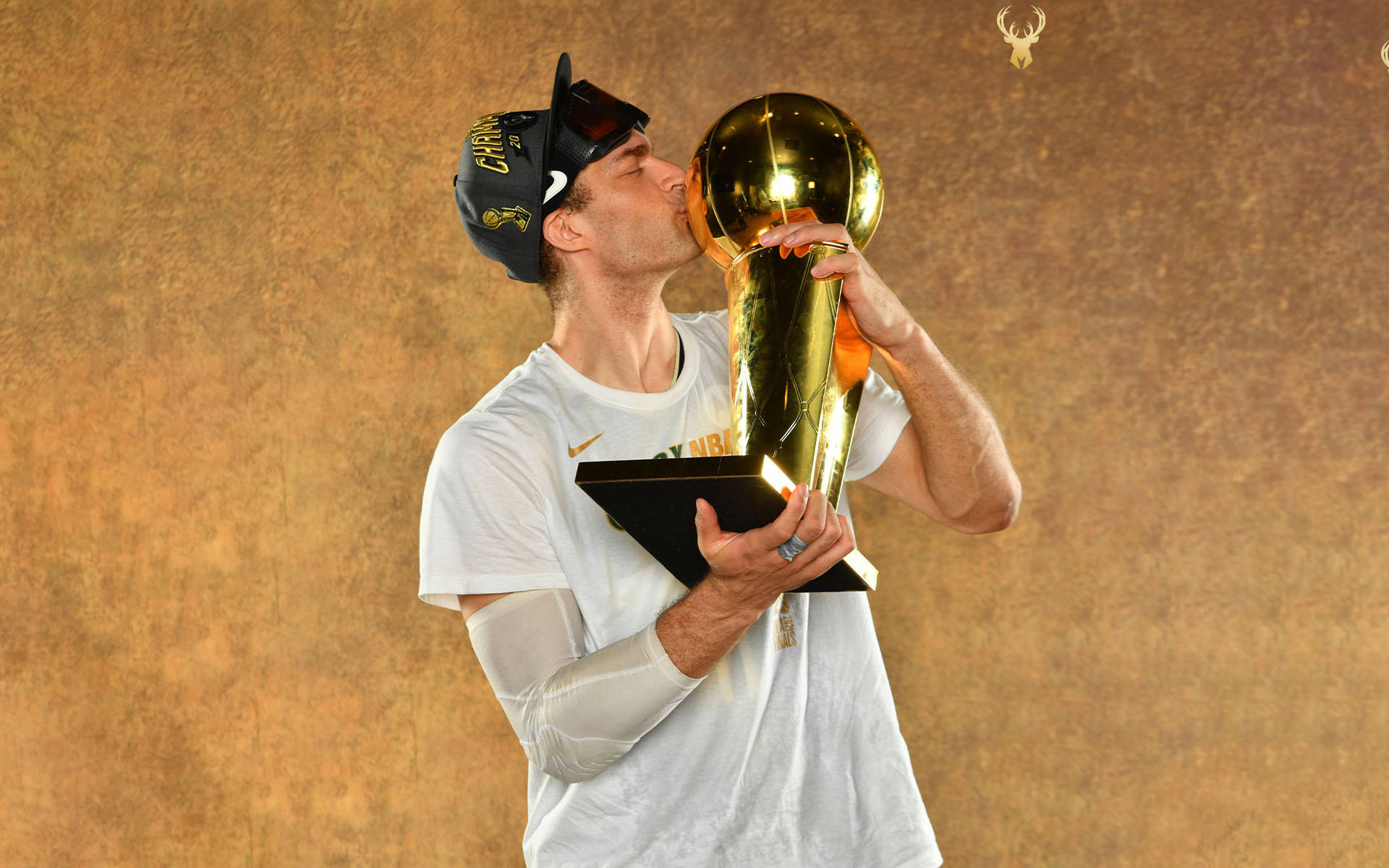 籃球運動員穿著白色球衣和帽子親吻NBA冠軍獎盃。 — Jordan Logo 壁紙