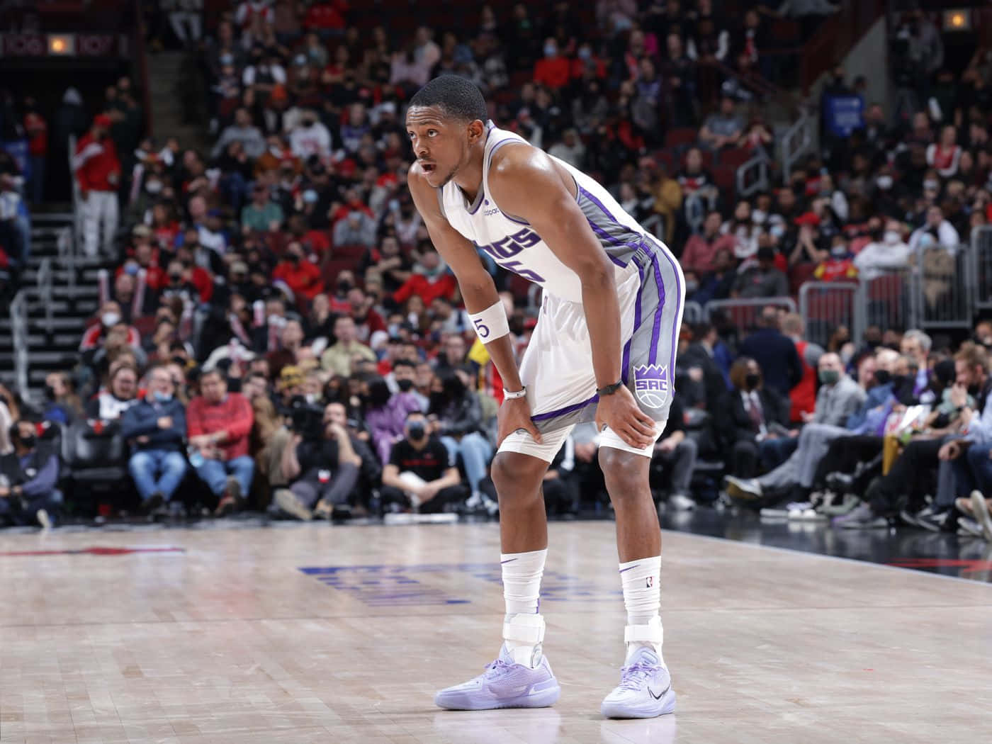 身穿白色和紫色球衣的籃球運動員在比賽中彎腰在球場上。 — NBA 壁紙