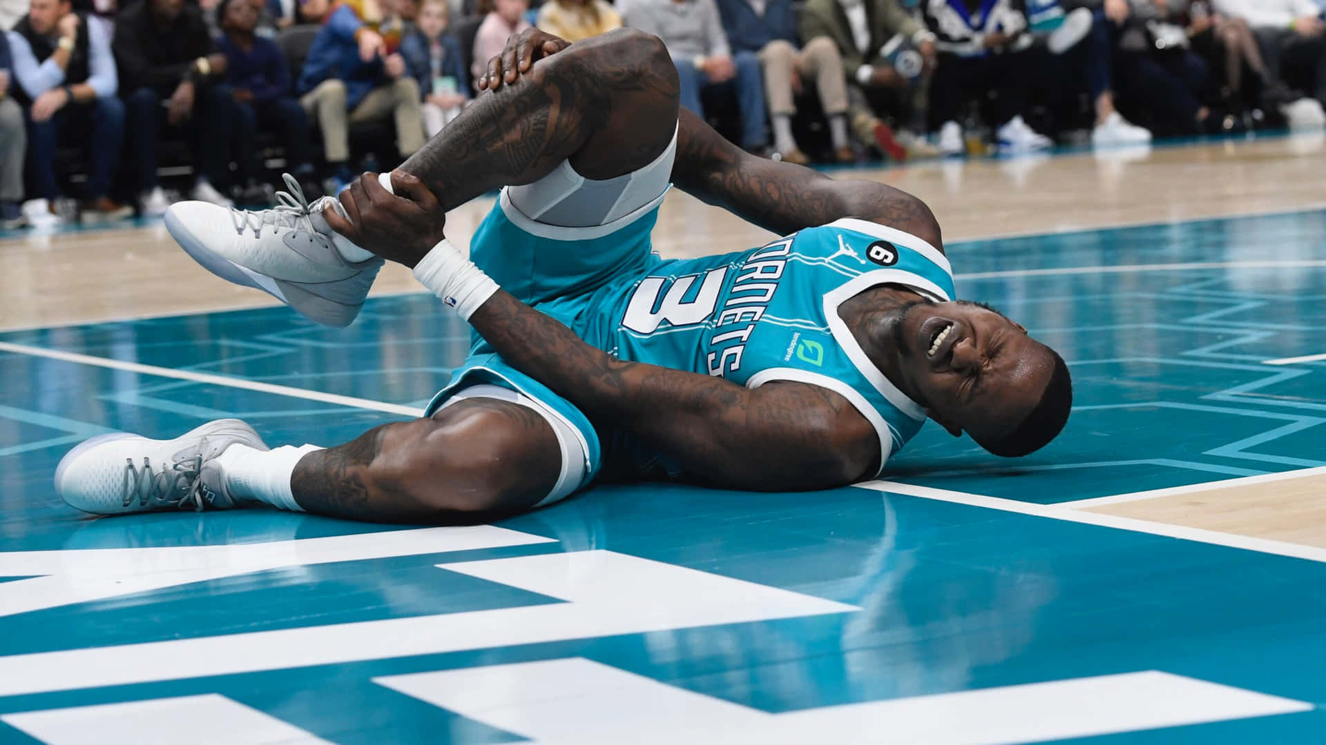 籃球運動員在藍色球場上痛苦地抓著膝蓋 — NBA 壁紙