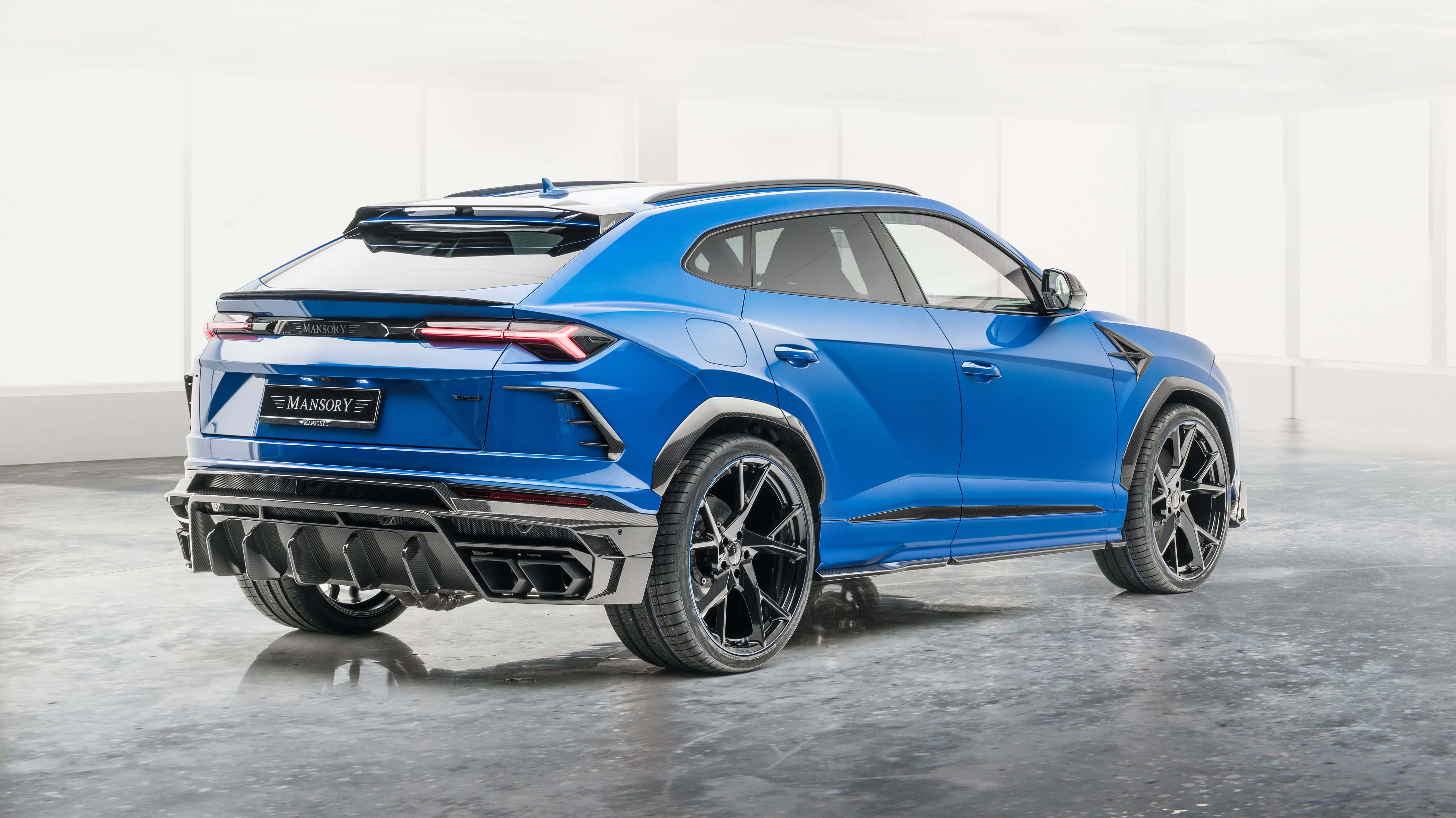 Lamborghini Urus 桌布 壁紙 — 一輛充滿活力的藍色Mansory改裝藍寶堅尼Urus SUV在簡約白色工作室中展示，地面為反光混凝土。