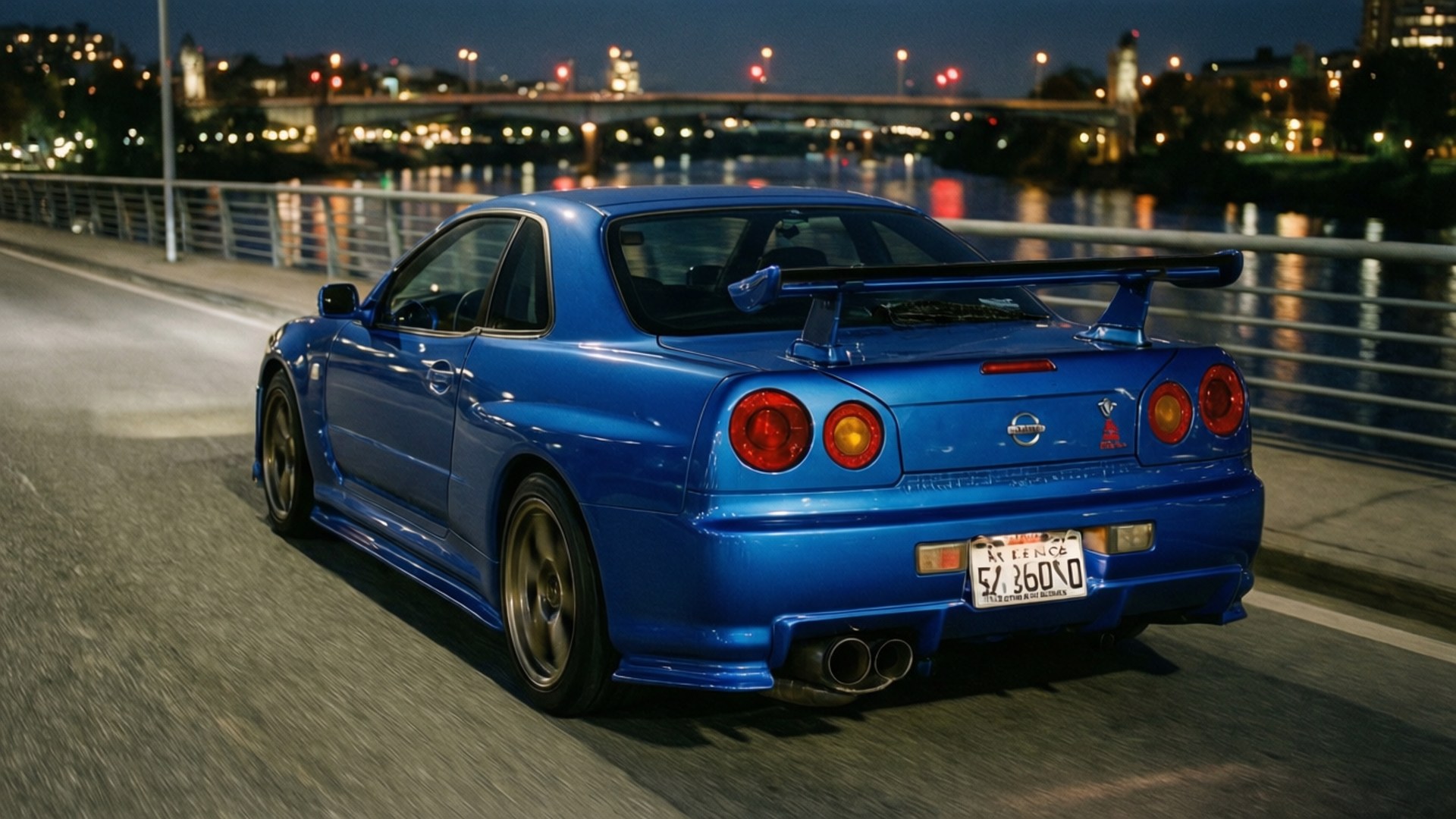 Midnight GT-R 壁紙 — 一輛充滿活力的藍色日產Skyline R34在夜間沿著城市橋樑飄移，背後發光的城市燈光倒映在水面上。