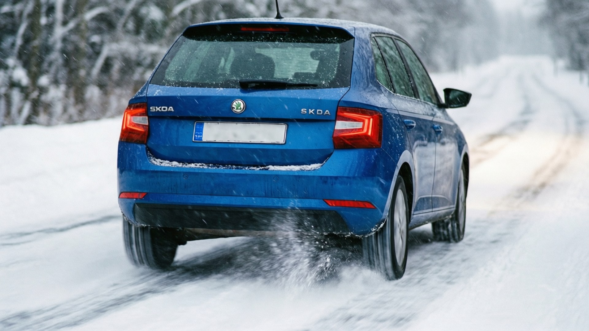 Skoda Fabia 桌布 壁紙 — 一輛藍色Skoda SUV在冬季道路上穿過深雪，雪花飄落，背景有樹木。