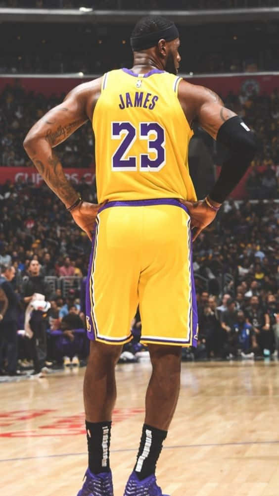 勒布朗詹姆斯身穿湖人球衣，雙手叉腰站在籃球場上。 — King Lebron James 壁紙