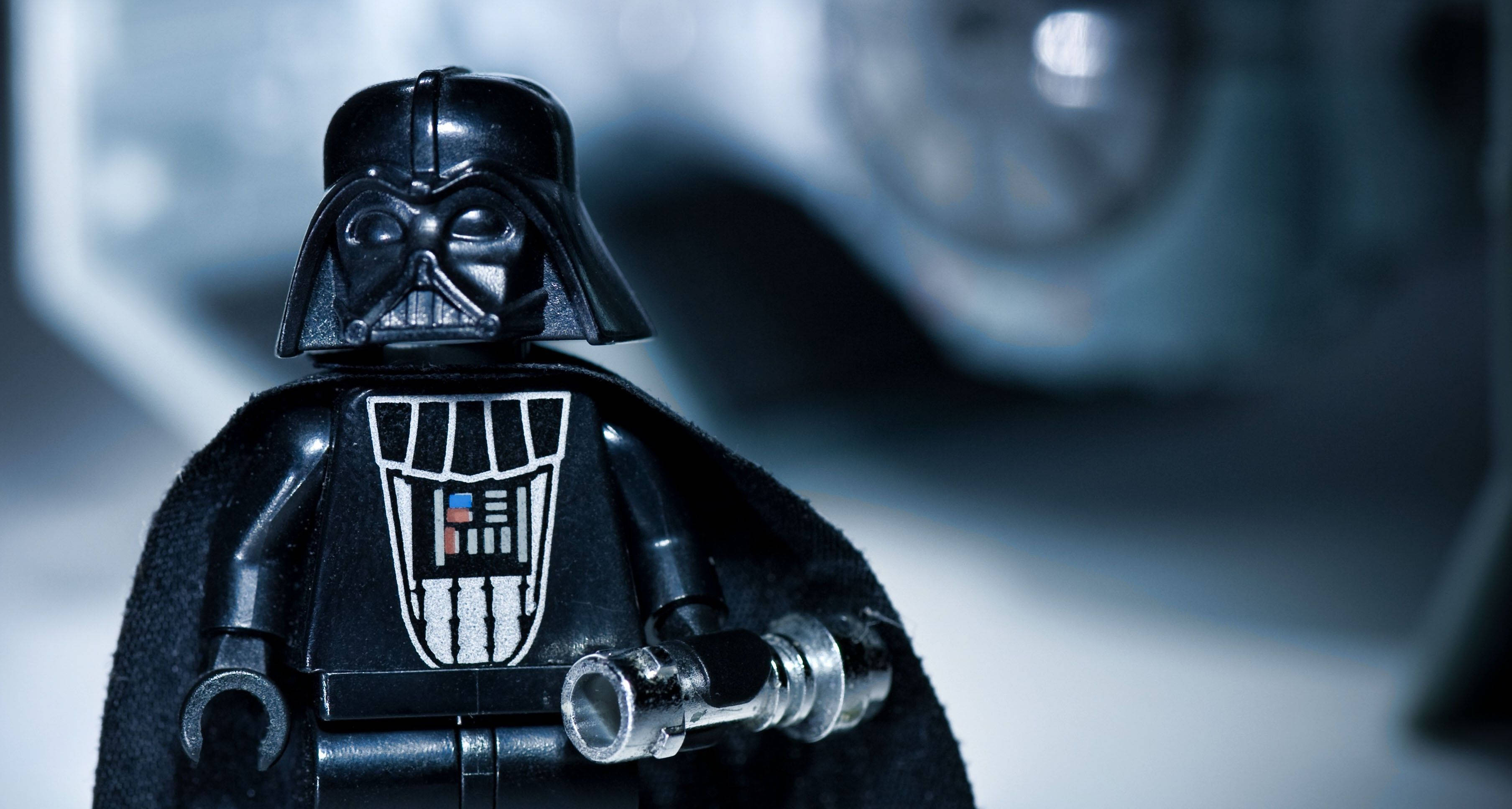 星際大戰 桌布 壁紙 — LEGO 黑武士迷你人偶特寫，身穿黑色盔甲，手持銀色光劍柄，背景模糊未來感。