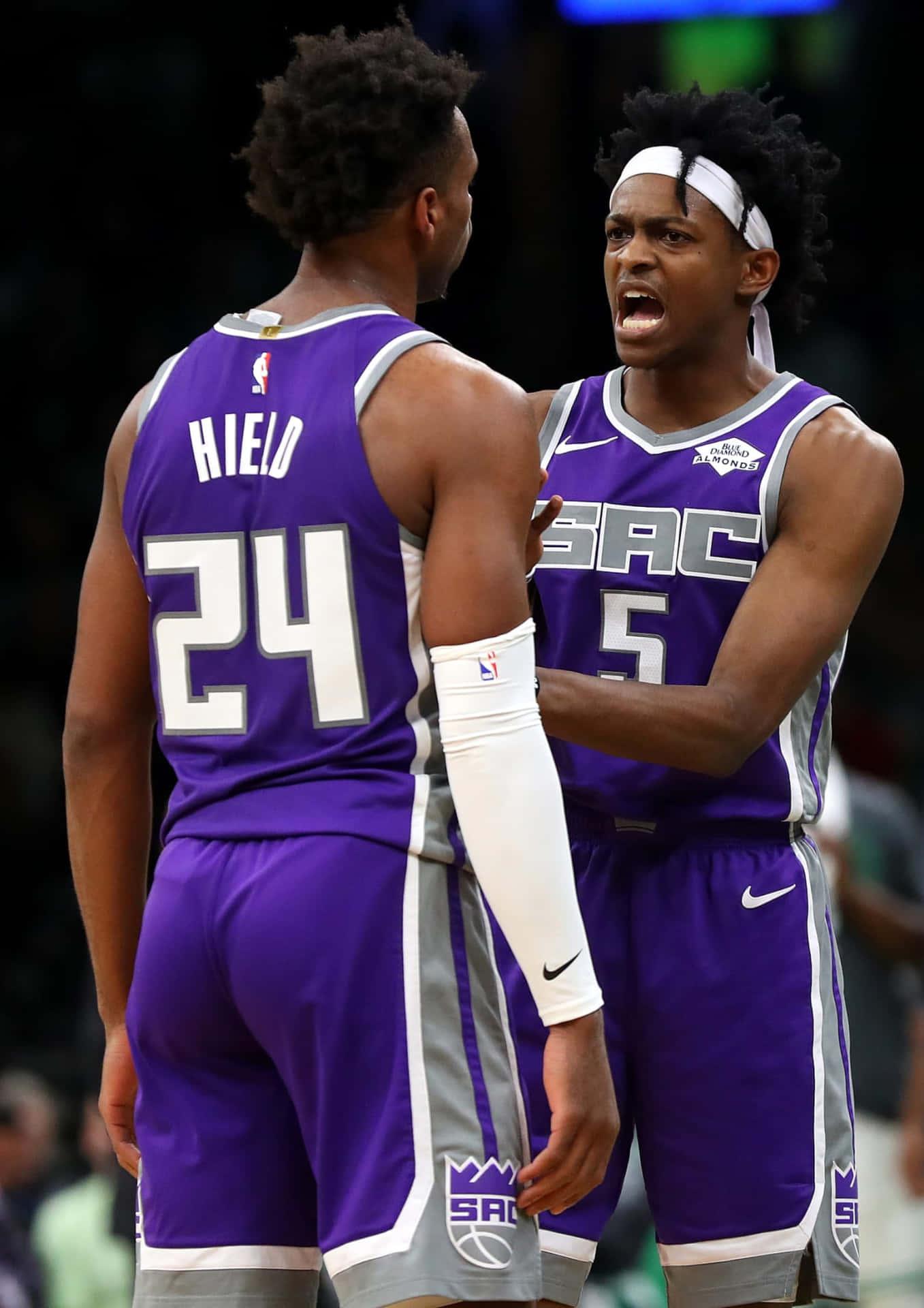 兩名身穿紫色球衣的NBA籃球運動員在球場上激烈交談。 — NBA 壁紙