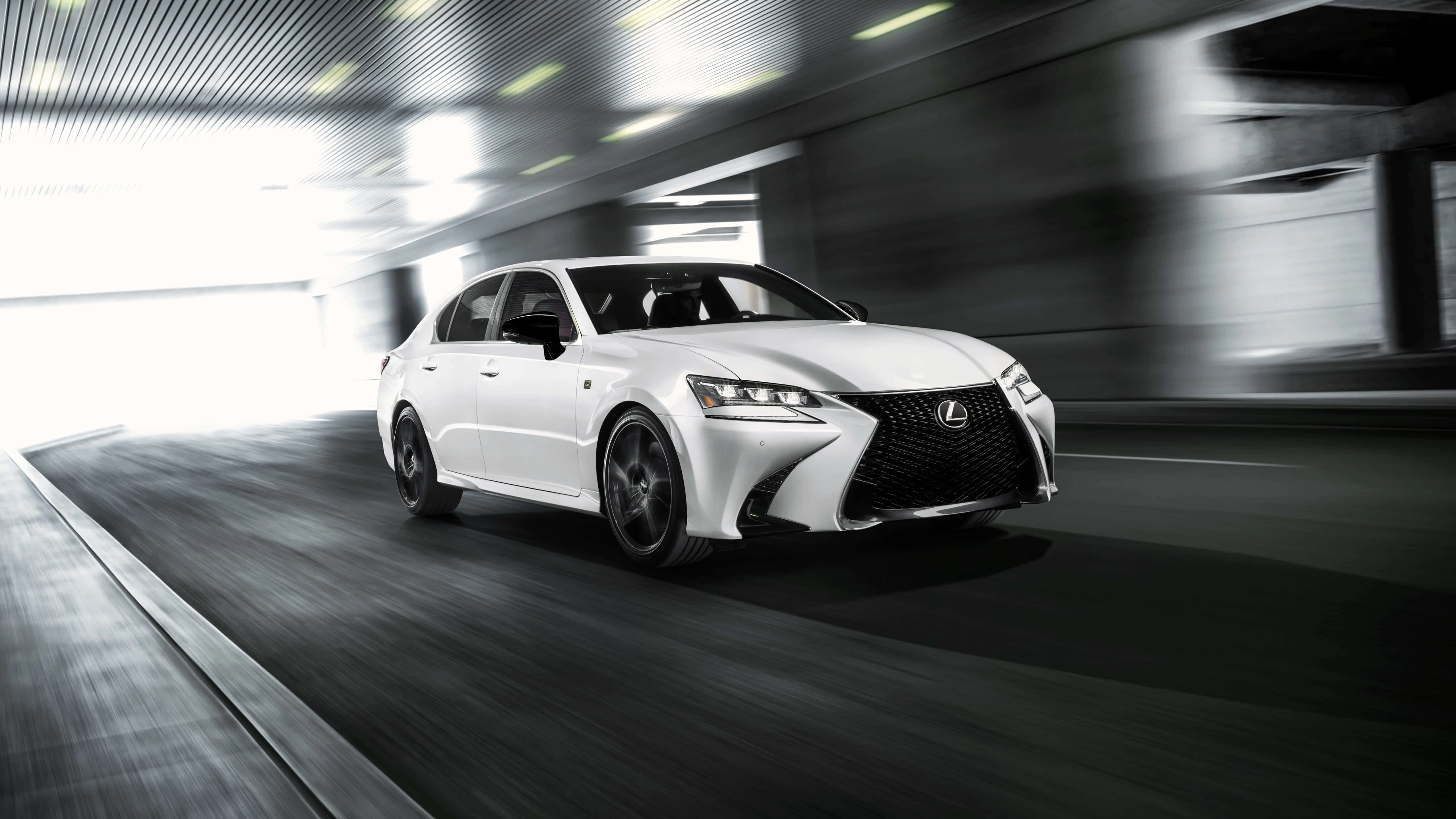 Lexus Gs F 桌布 壁紙 — 一輛時尚的白色Lexus轎車在現代隧道中疾馳，動態模糊強調了速度。