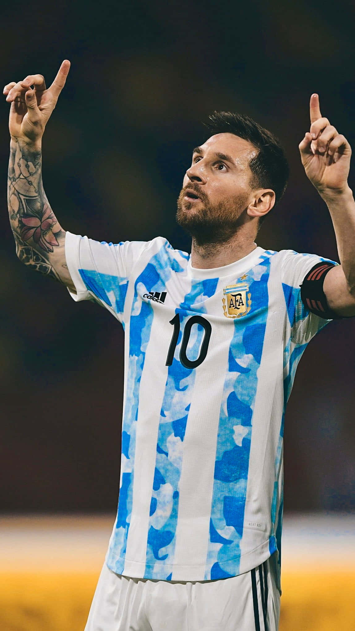 Messi 2022 桌布 壁紙 — 利昂內爾·梅西身穿阿根廷藍白條紋球衣，在夜間足球比賽中高舉雙食指慶祝勝利。