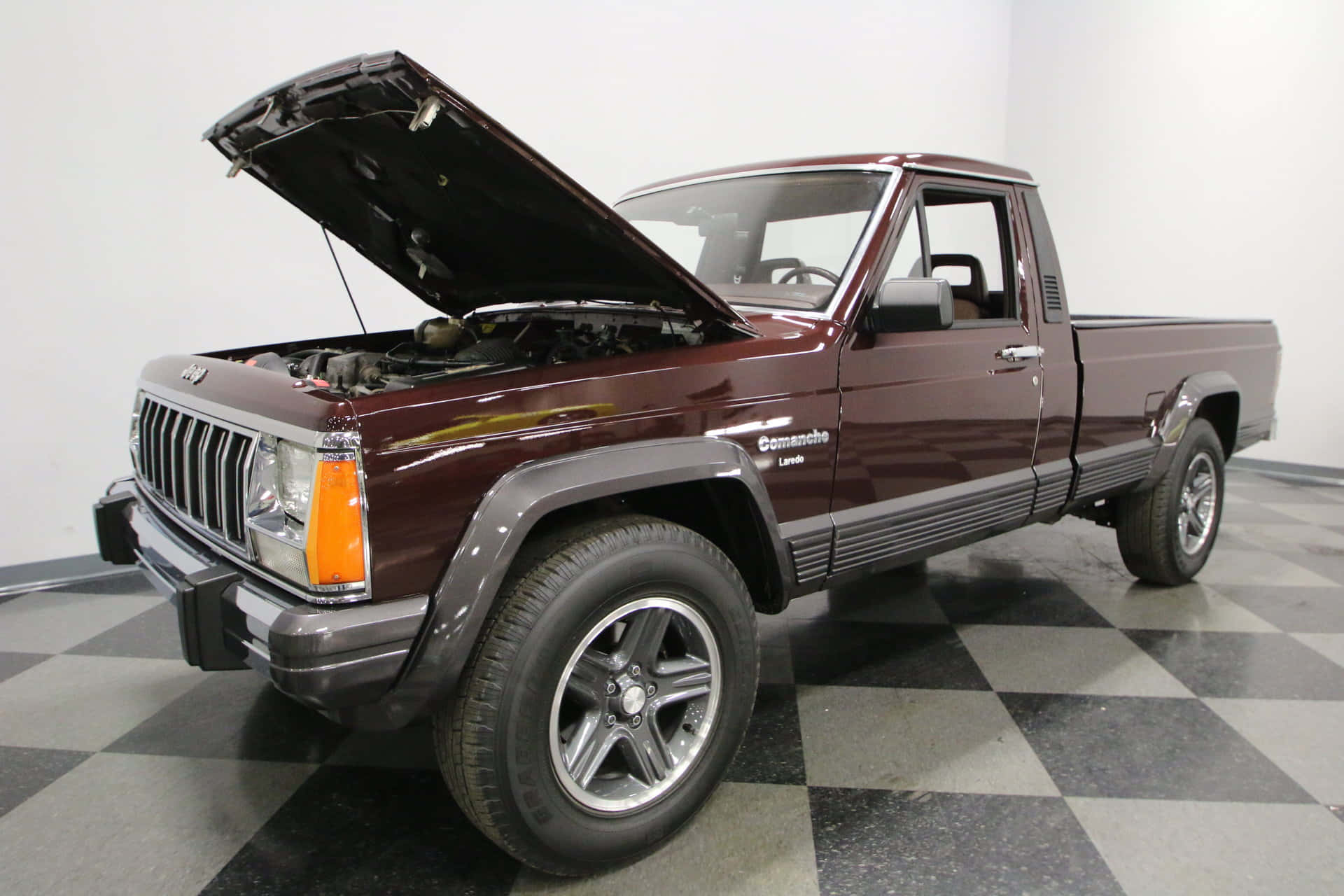 Jeep Comanche 桌布 壁紙 — 一輛栗色Jeep Comanche皮卡車打開引擎蓋，停在明亮工作室的黑灰格子地板上。