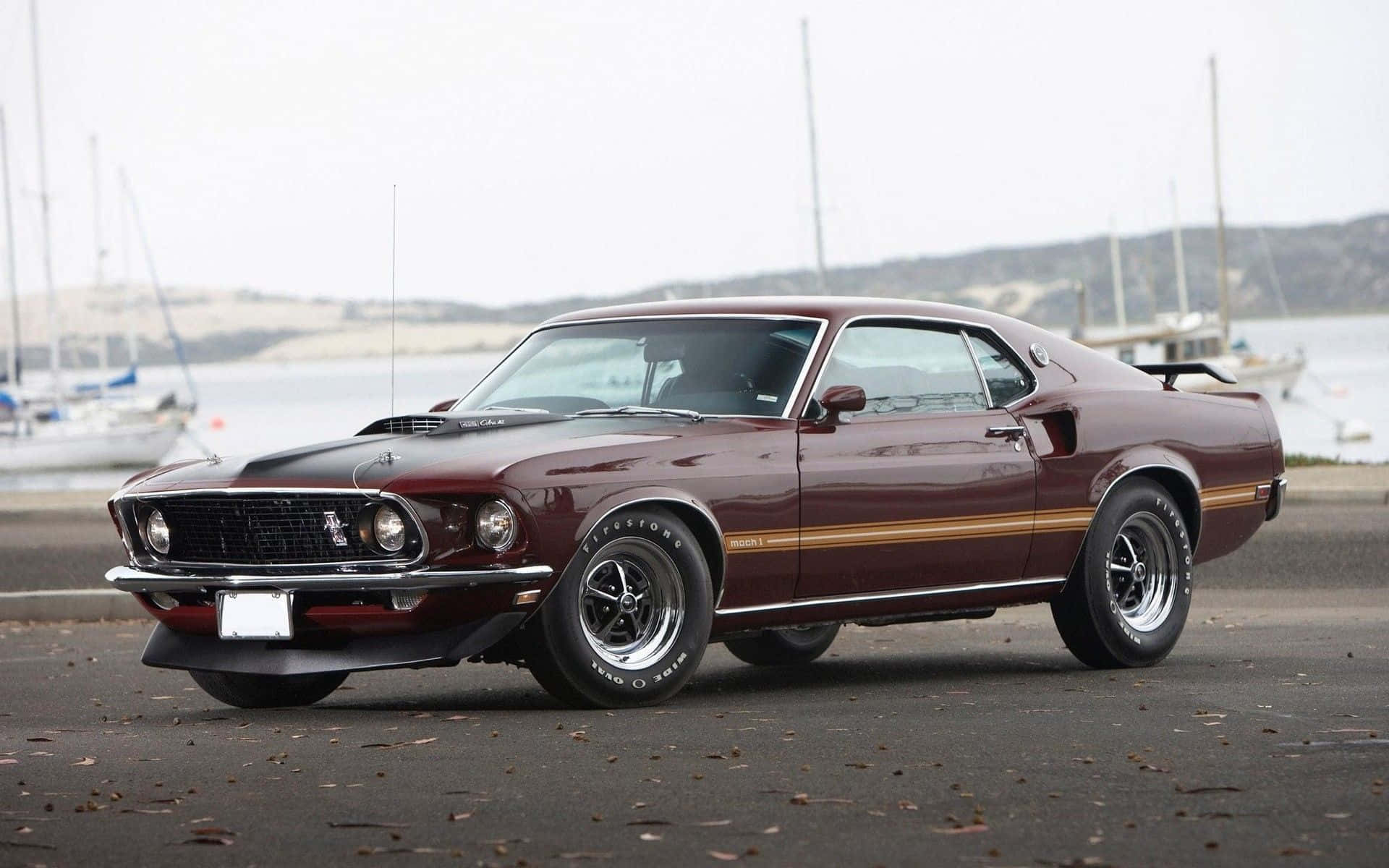 Ford Mustang Mach 1 桌布 壁紙 — 一架栗色經典肌肉車帶金色條紋停泊在碼頭，背景有帆船。