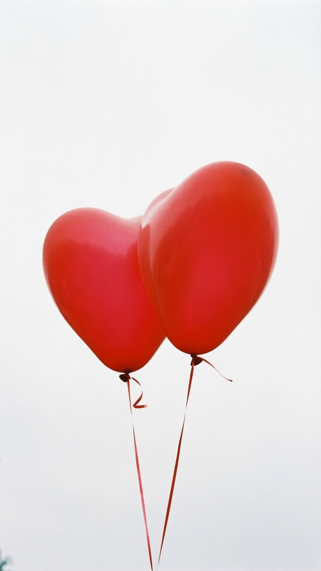 Valentine Free 桌布 壁紙 — 兩個光滑的紅色心形氣球在柔和的多雲天空中輕輕漂浮。
