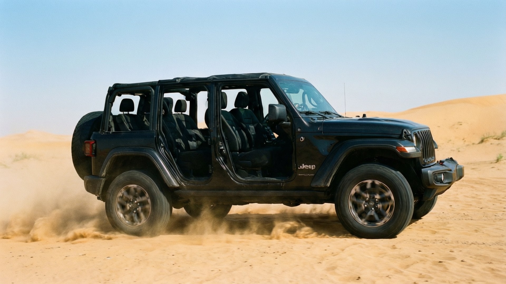 Desert Dune Off-Road 壁紙 — 一輛黑色Jeep Wrangler無門車在晴朗藍天下咆哮著穿過金色沙漠沙丘，揚起沙塵。