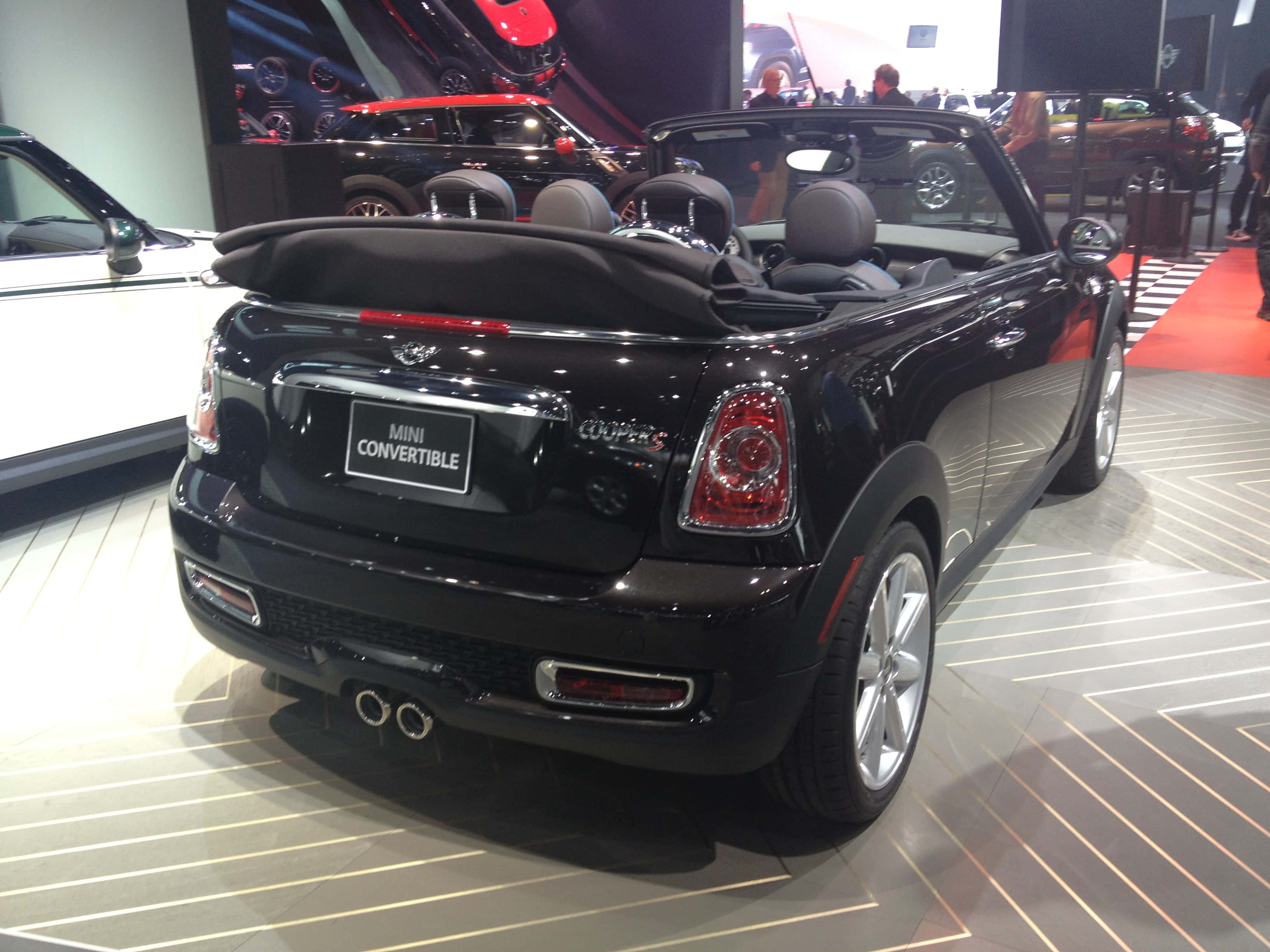 Mini Cooper S Convertible 桌布 壁紙 — 一輛亮黑色MINI Convertible在車展上展示，車篷敞開，停在條紋地板上，燈光明亮。