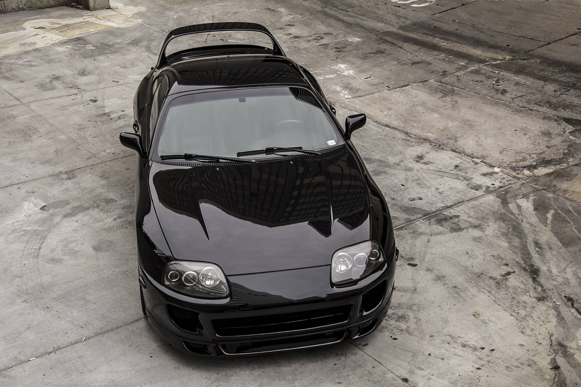 黑色跑車停在裂縫混凝土路面上 — Toyota Supra 壁紙