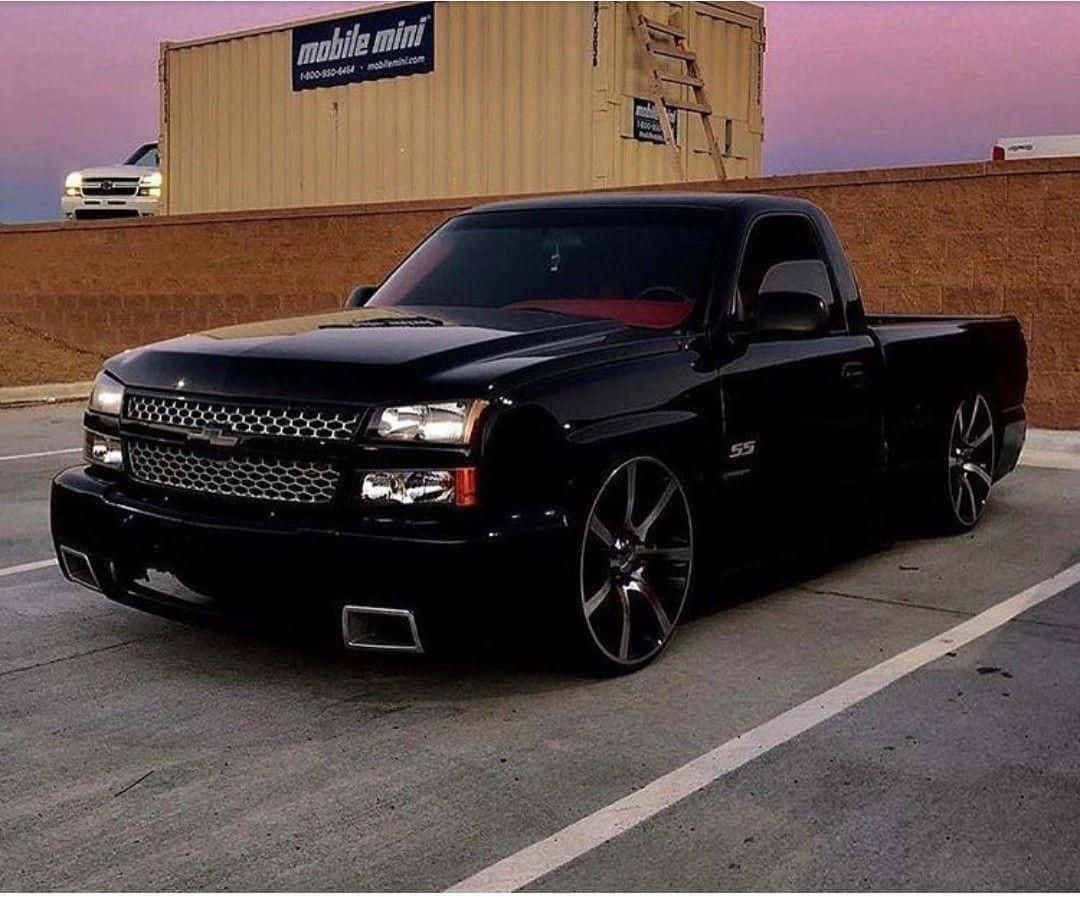  壁紙 — 一輛亮黑色雪佛蘭Silverado SS pickup卡車停放在停車場，黃昏時分，粉紅色天空在貨櫃後面。