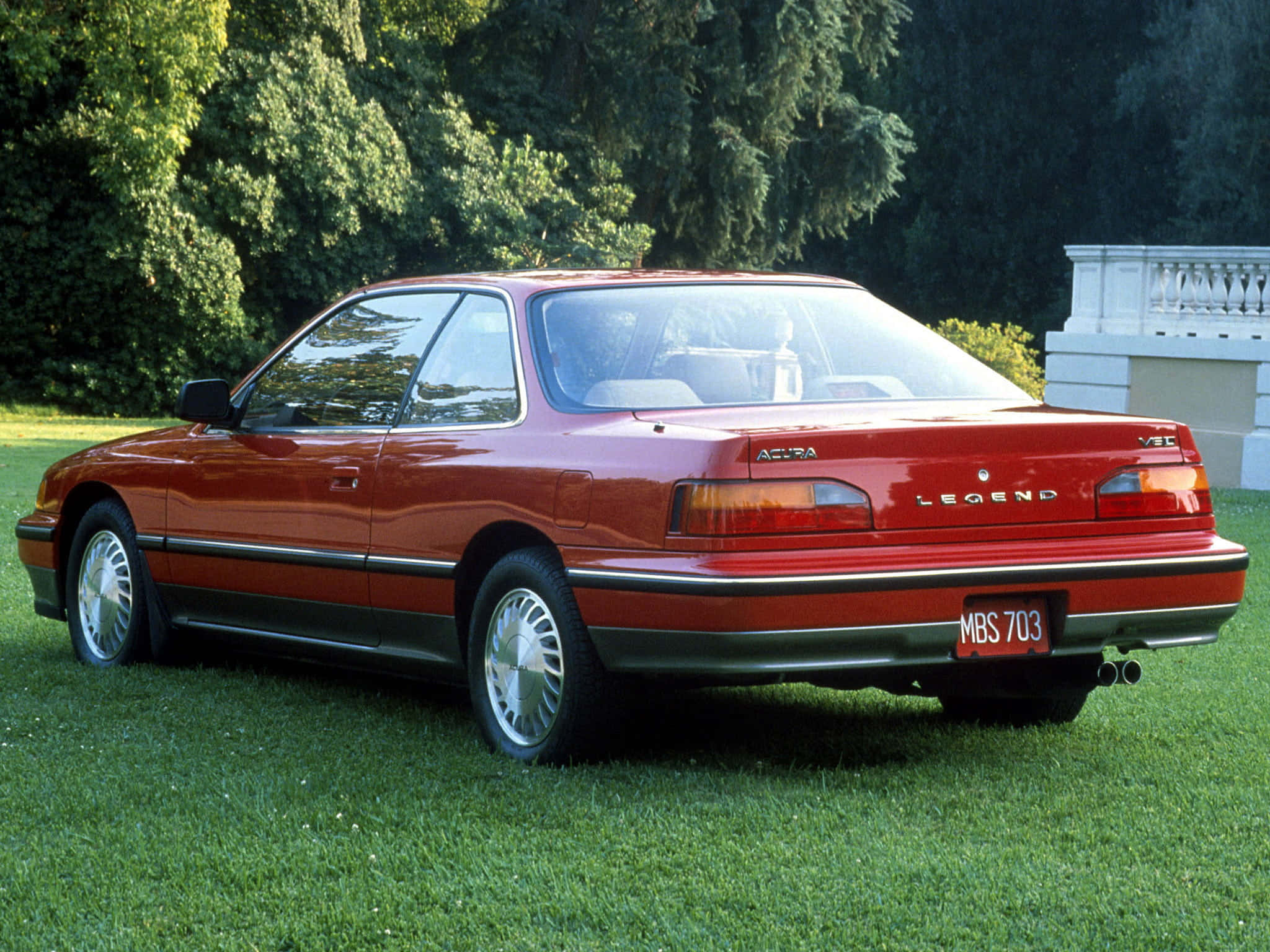 Acura Legend 桌布 壁紙 — 一輛亮紅色Acura Legend轎跑車停放在茂盛綠色草坪上，背景有樹木和白色欄杆。