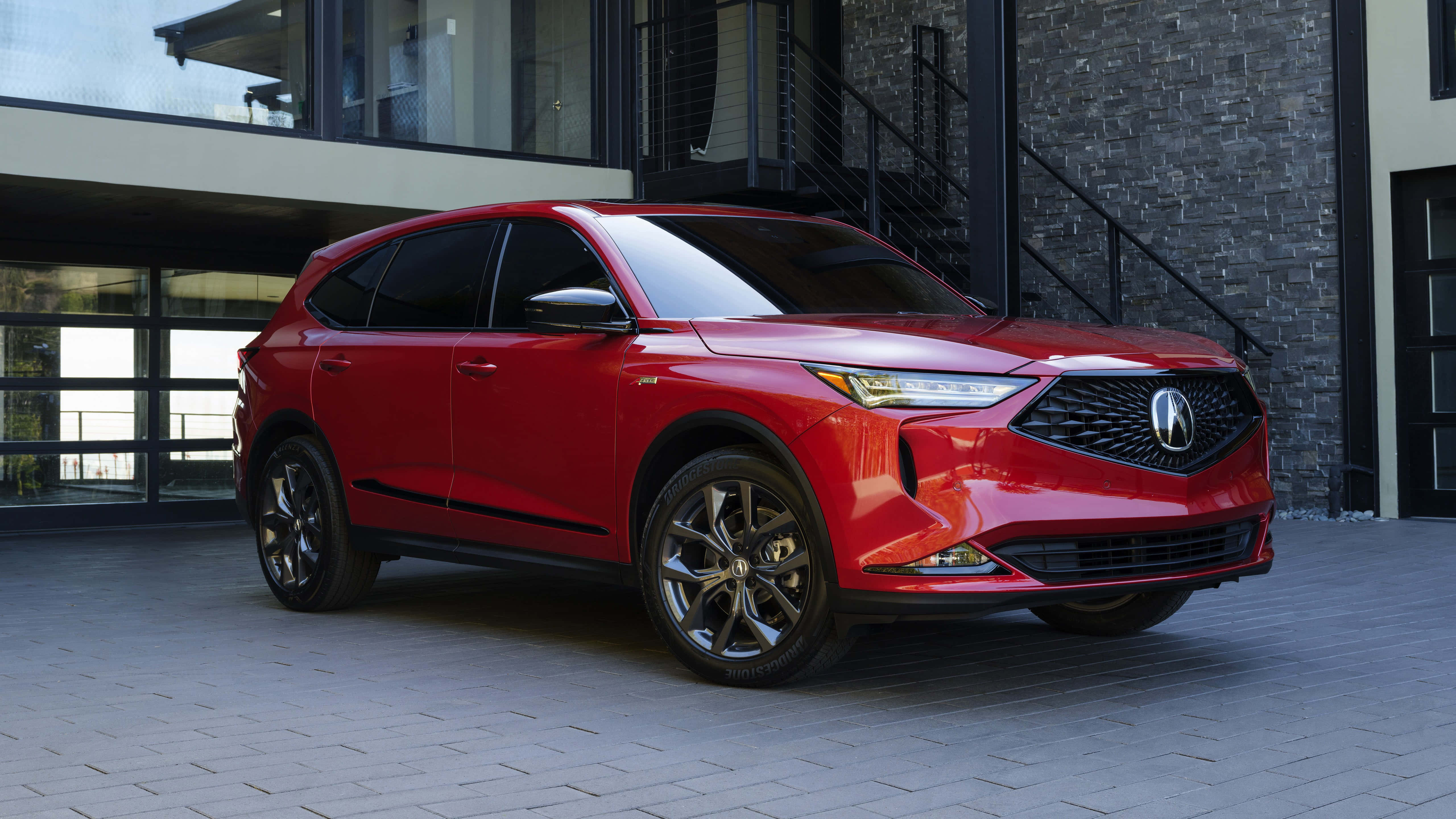 Acura Mdx 桌布 壁紙 — 一輛亮紅色Acura SUV停放在現代石頭和玻璃建築前的鋪砌庭院。